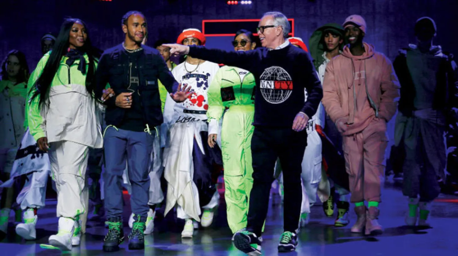 تومي هيلفيغر في نهاية عرضه مع لويس هاملتون والمغنية «إتش إي آر»