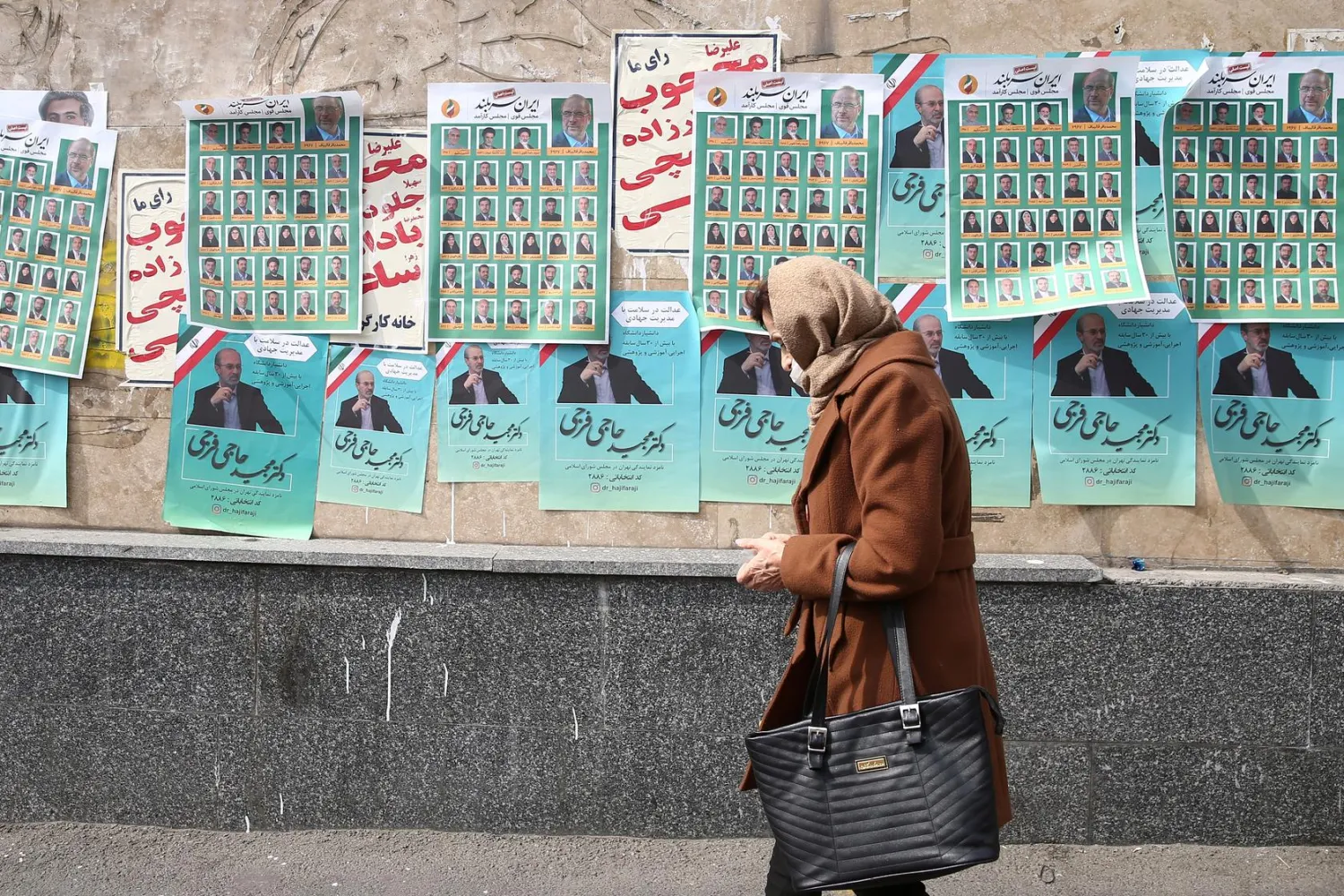 A woman walks past parliamentary election campaign posters in Tehran, Iran February 19, 2020. WANA (West Asia News Agency)/Nazanin Tabatabaee via REUTERS