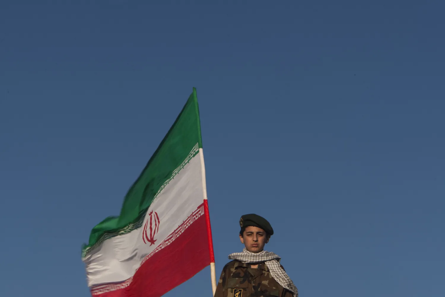 Member of Iran's Revolutionary Guard stands next to Iranian flag during a ceremony in Azadi Square in Tehran. (Reuters)