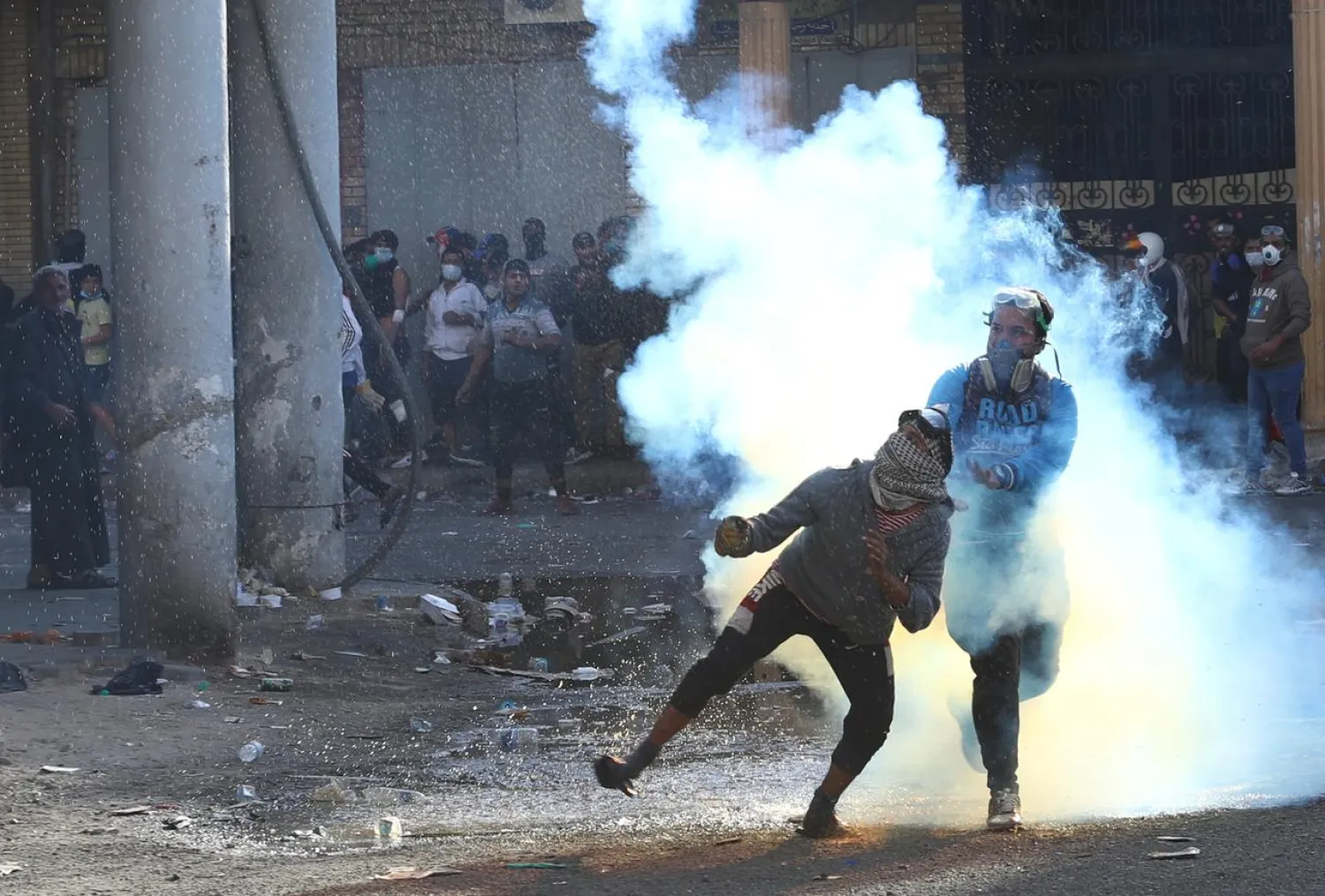 An Iraqi demonstrator throws away a tear gas canister during the ongoing anti-government protests in Baghdad, Iraq November 22, 2019. REUTERS/Thaier al-Sudani