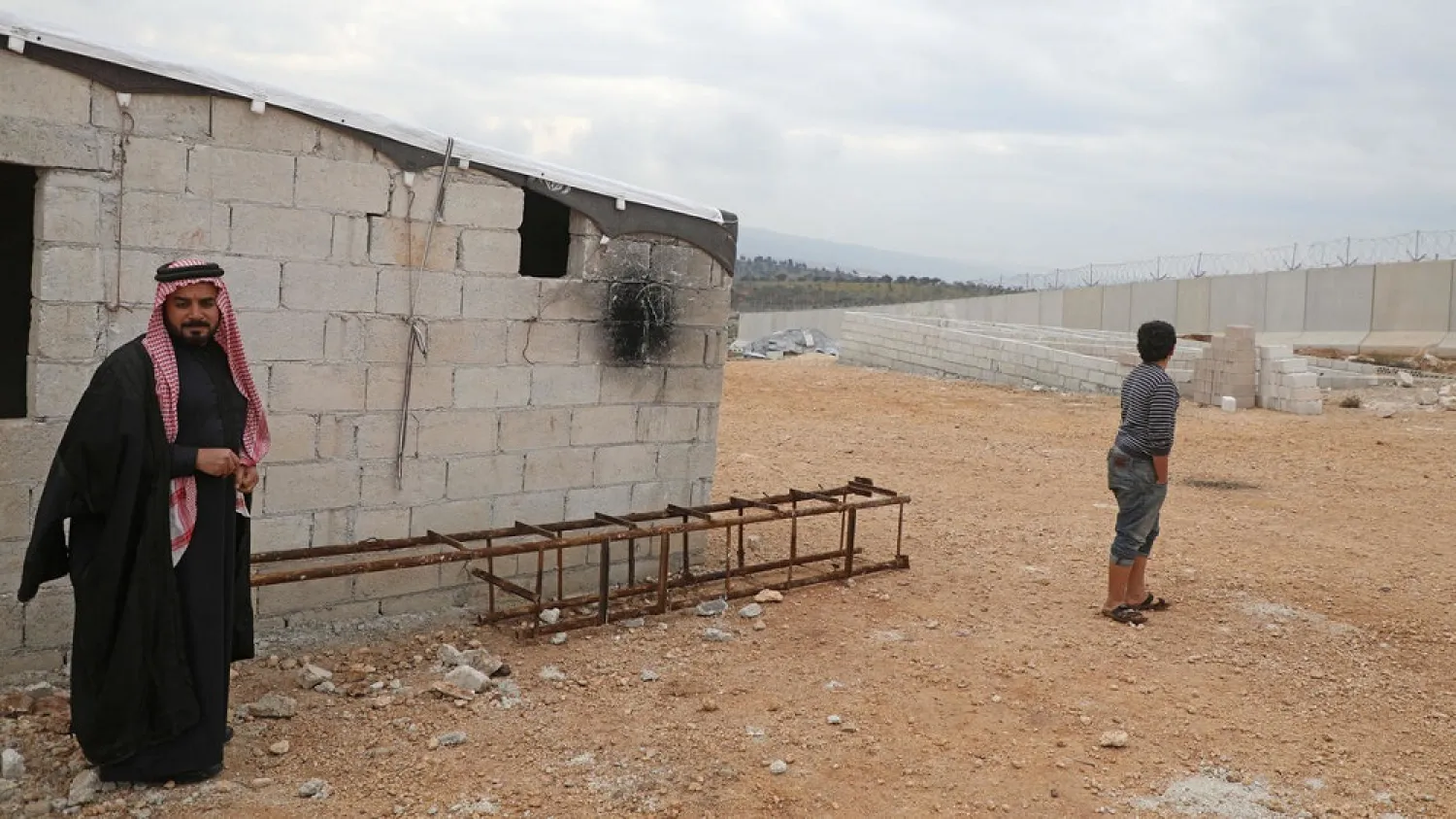 Abu Jaber stands next to a ladder which he built to climb over the Turkish border wall at a camp for the displaced in northwest Syria's province of Idlib. (AFP)
