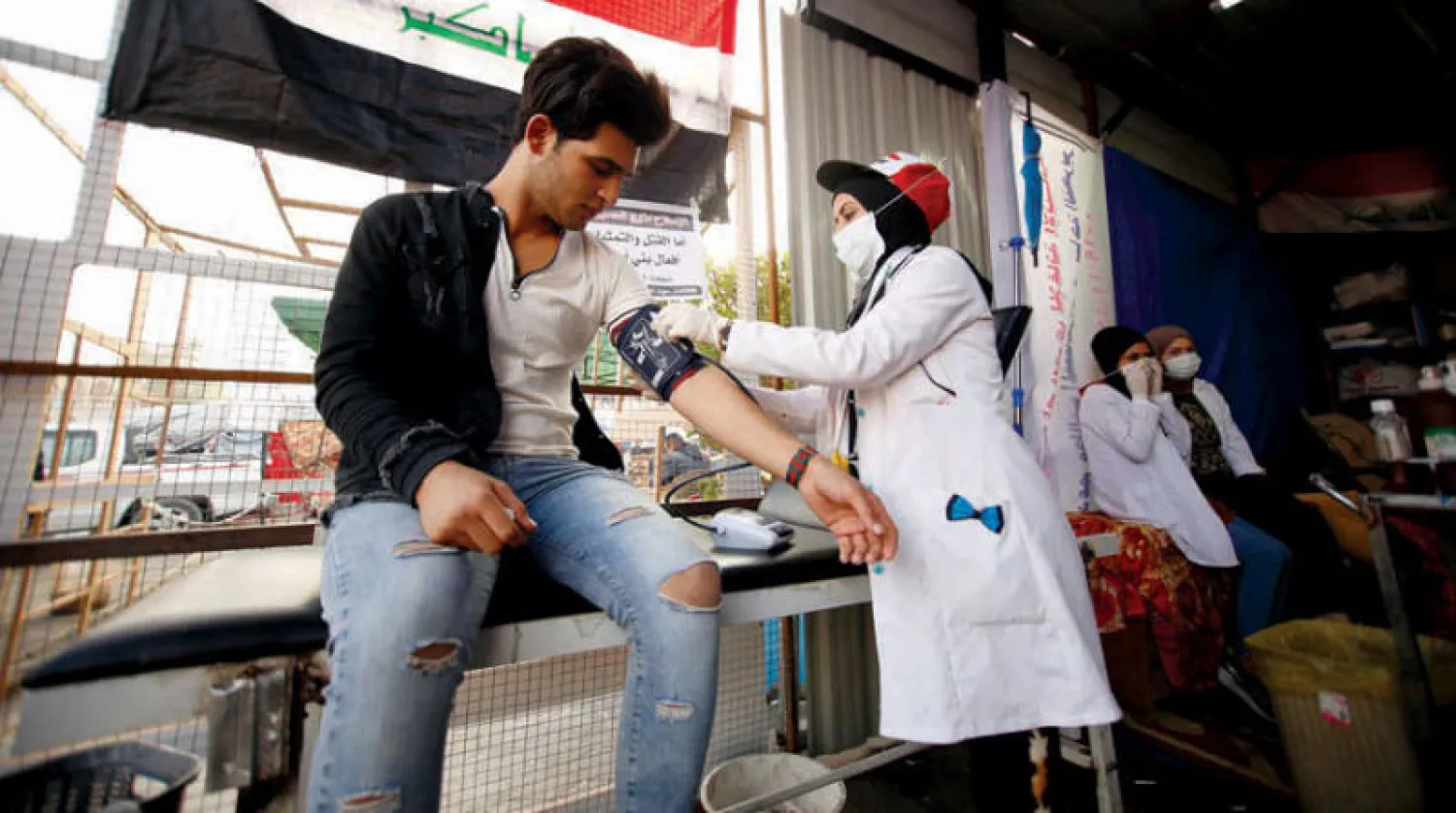 هناء جاسم تقيس ضغط دم أحد المتظاهرين في ساحة التحرير (رويترز)