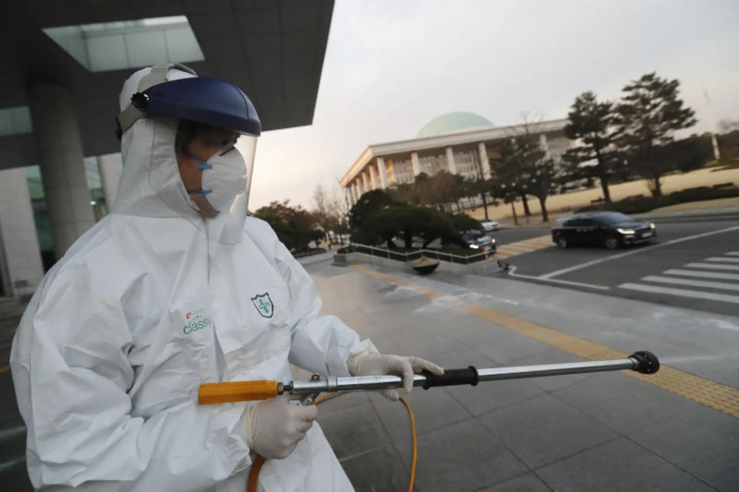 عامل يرش المطهر في سيول كإجراء احترازي في إطار جهود مكافحة فيروس كورونا (أ.ب)