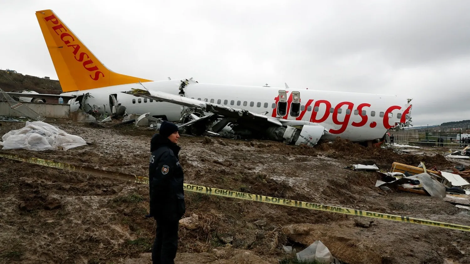 A police officer stands guard near the wreckage of a Pegasus Airlines plane that overran the runway during landing and crashed, Istanbul's Sabiha Gokcen airport, Turkey, Feb. 6, 2020. (Reuters)