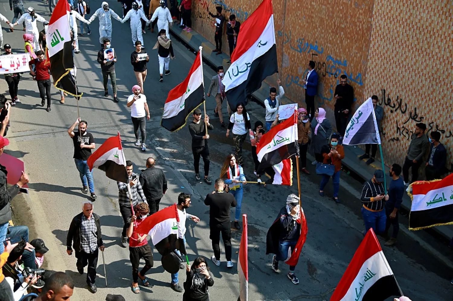 Students and other demonstrators hold national flags during ongoing anti-government protests, in Baghdad, Iraq, Sunday, Feb. 23, 2020. (AP)