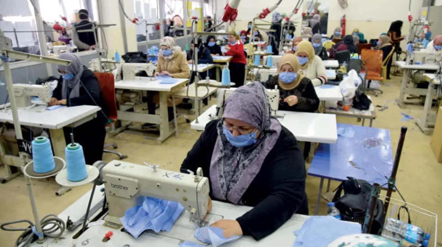 عراقيات يصنعن كمّامات واقية في مصنع بالموصل أمس (إ.ب.أ)