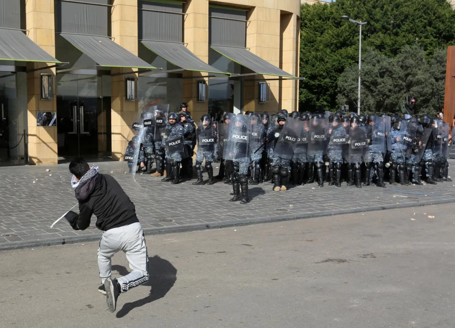 A protestor throws a stone at the riot police during a protest against the political elite in Beirut, Lebanon January 27, 2020. REUTERS/Aziz Taher