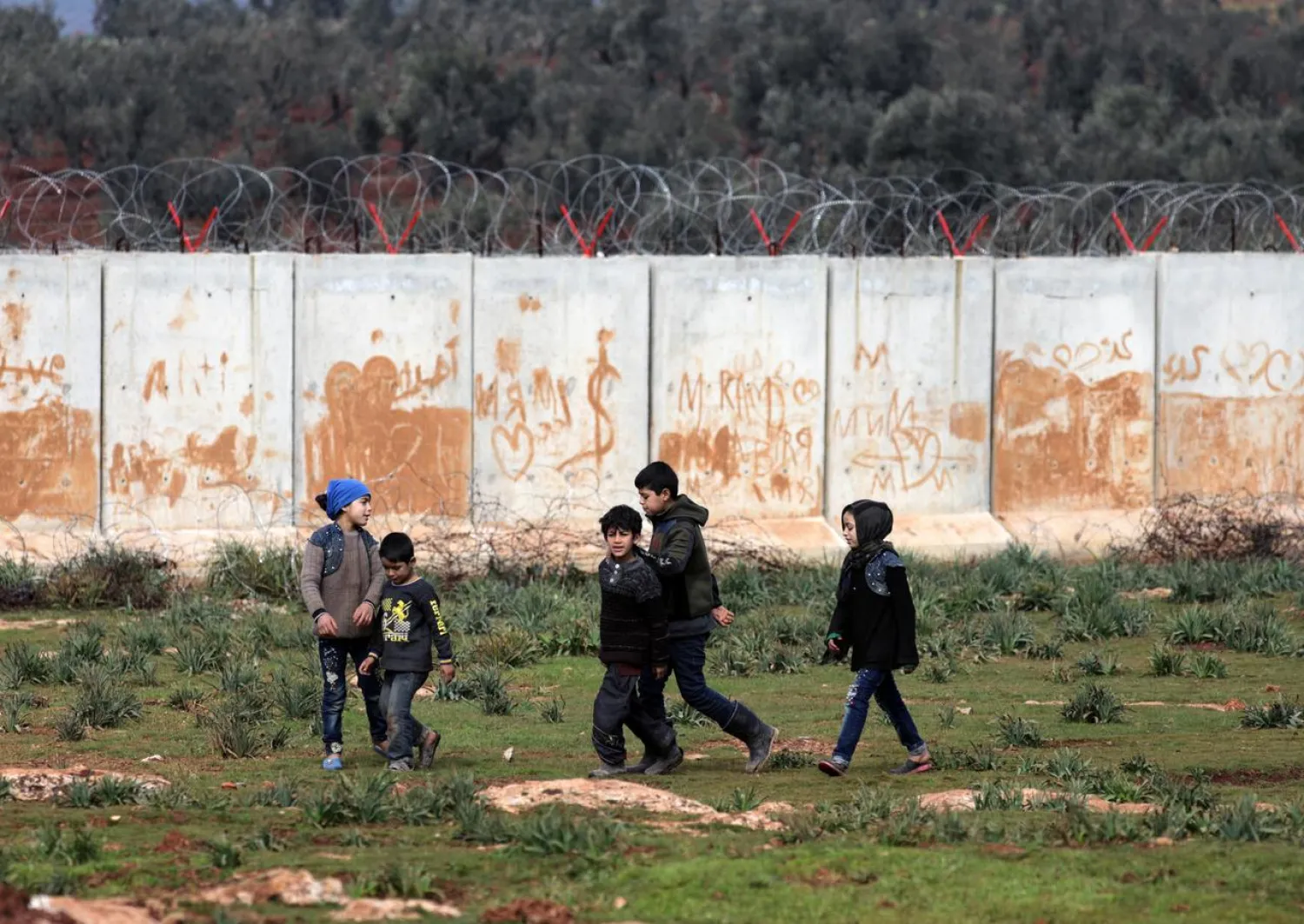 Internally displaced boys walk near the wall in Atmah IDP camp, located near the border with Turkey, Syria February 24, 2020 | REUTERS