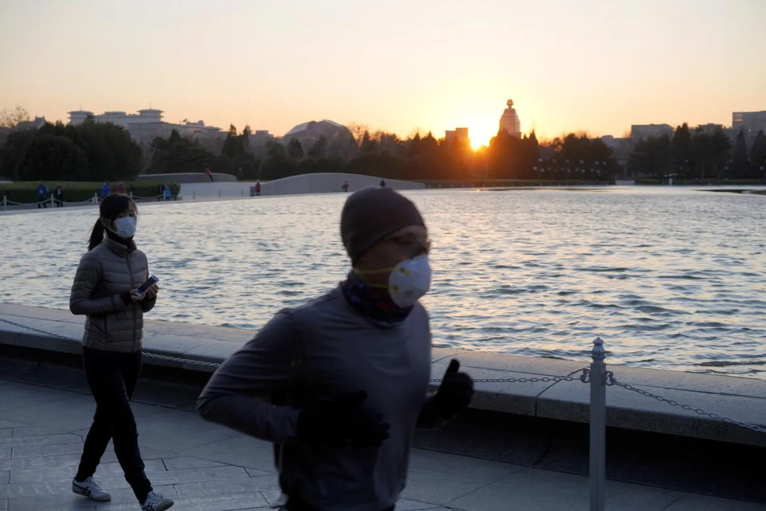 A man wearing a face mask jogs near the National Center for the Performing Arts, following an outbreak of the novel coronavirus in the country, in Beijing, China February 22, 2020. REUTERS/Stringer