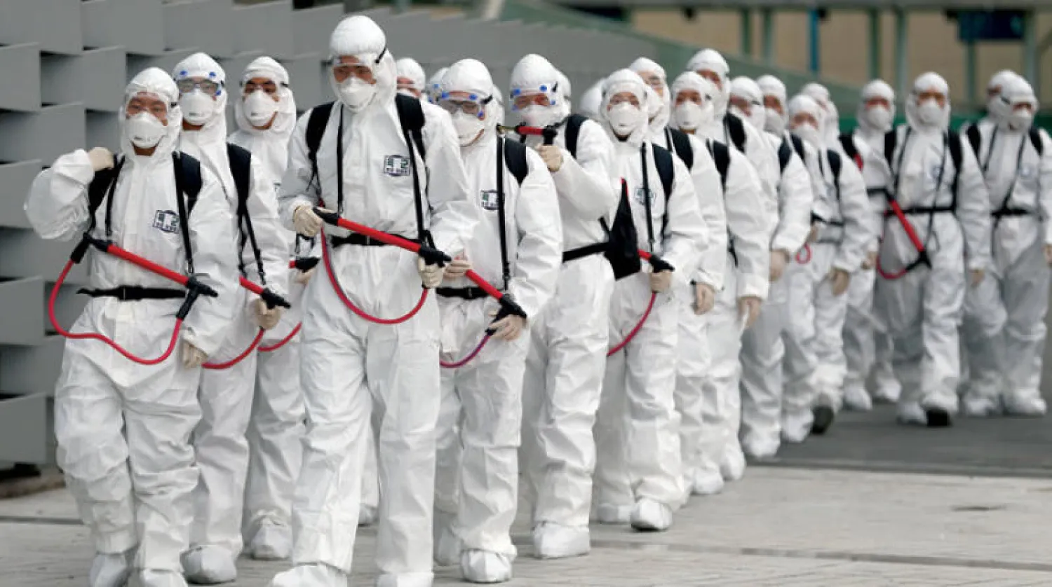 جنود كوريون جنوبيون بملابس واقية ينظفون محطة نقل بالقطارات في ديغو التي ينتشر فيها فيروس كورونا (أ.ف.ب)