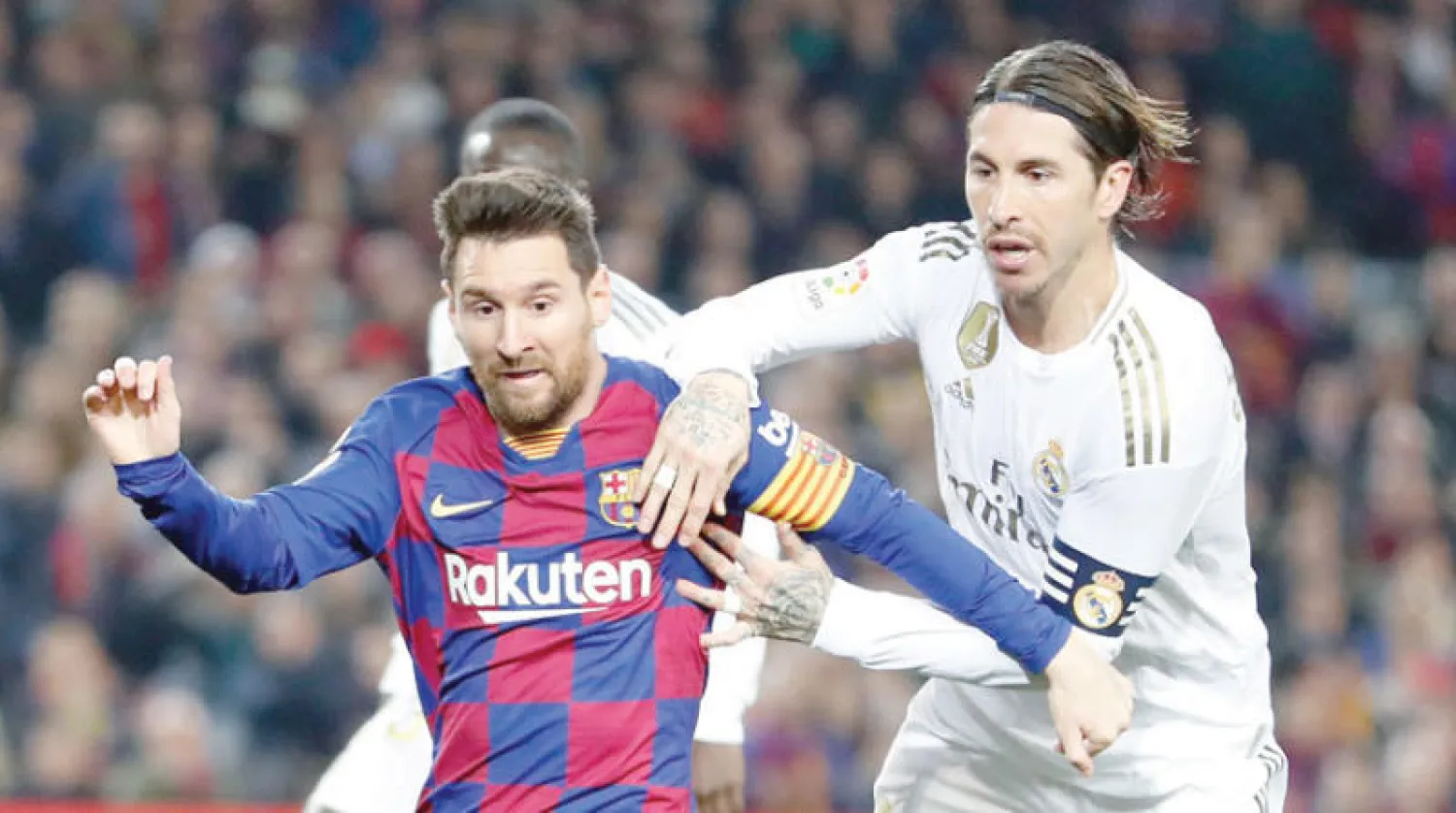 ميسي وراموس يتحفزان لقمة جديدة بين برشلونة والريال (إ.ب.أ)