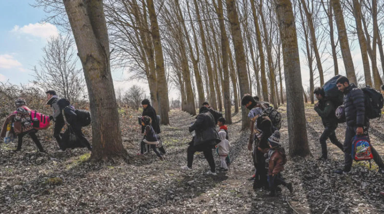 لاجئون سوريون مع أطفالهم على الحدود التركية - اليونانية في إدرنة أمس بعد سماح تركيا لهم بالانطلاق (إ.ب.أ)