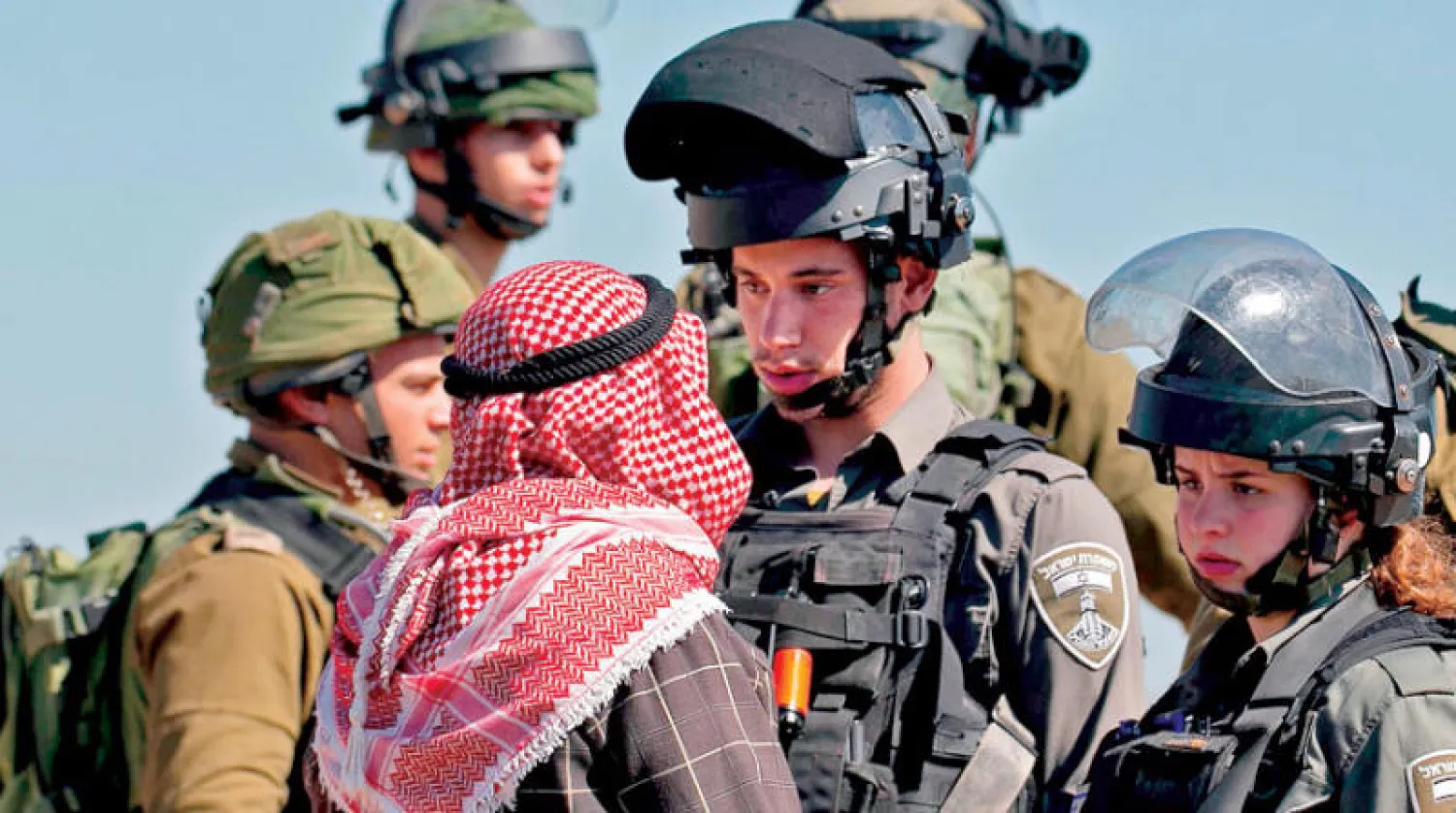 فلسطيني يصطدم بقوات إسرائيلية في عقربا بالضفة أمس مع انطلاق بناء استيطاني في الجوار (أ.ف.ب)