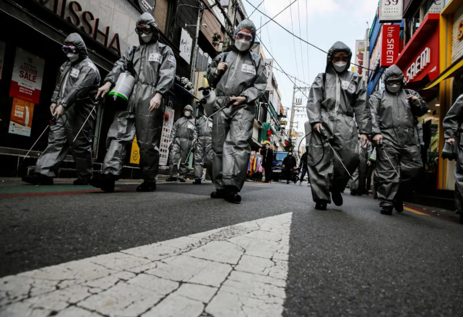 جنود كوريون جنوبيون يرتدون ملابس واقية يقومون بتنظيف شارع للتسوق في سيول (رويترز)