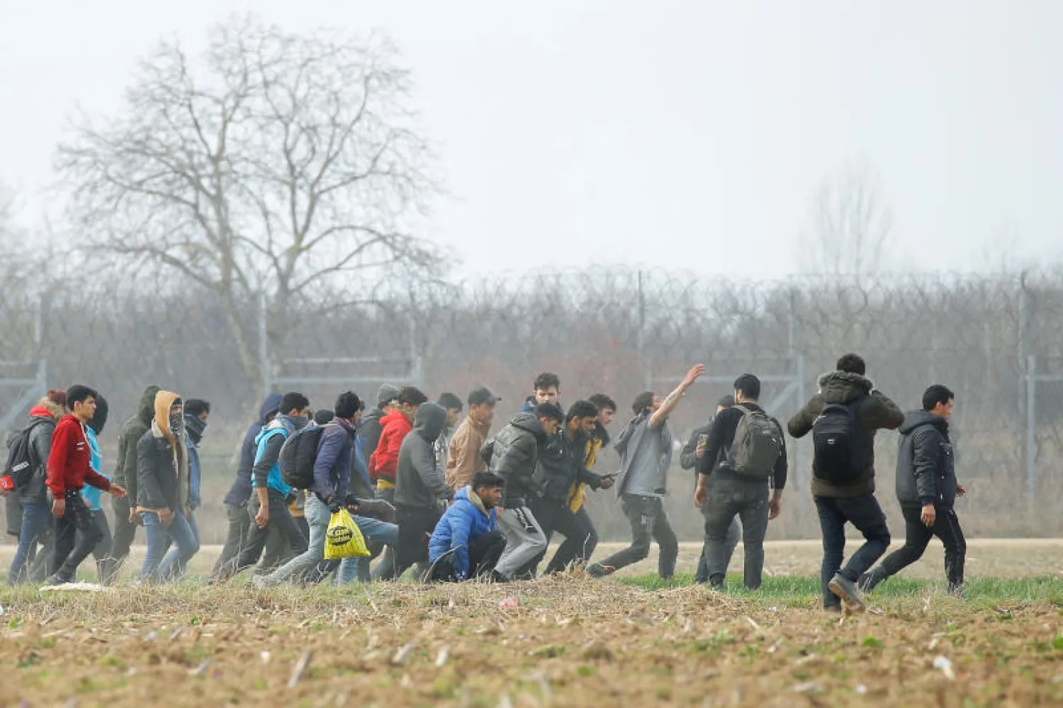 مهاجرون ينقلون جريحاً في الجانب التركي من الحدود مع اليونان (رويترز)