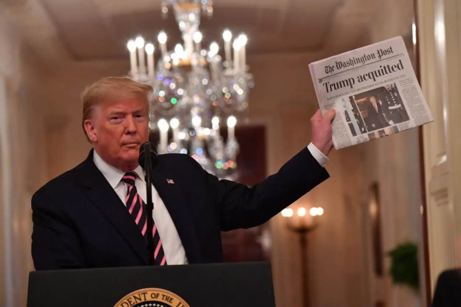 Senato'daki müttefikleri tarafından azil soruşturmasından aklanan Donald Trump, Beyaz Saray'da destekçilerine hitap ederken "The Washington Post" gazetesini tutuyor (AFP)