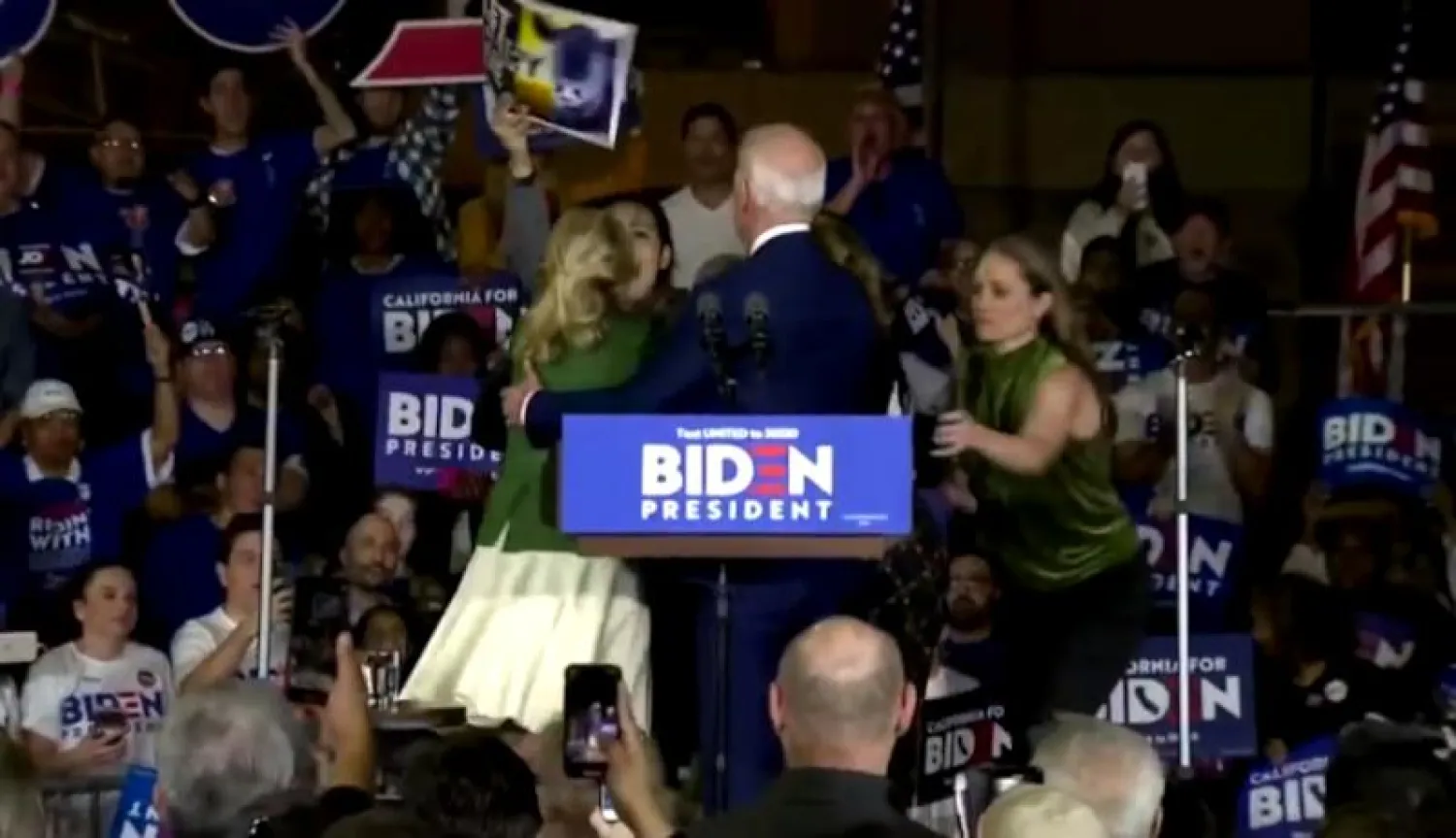 صورة مقتبسة من فيديو لصعود محتجة إلى المنصة التي يقف عليها المرشح الديمقراطي للرئاسة جو بايدن برفقة زوجته جيل خلال تجمع انتخابي (رويترز)