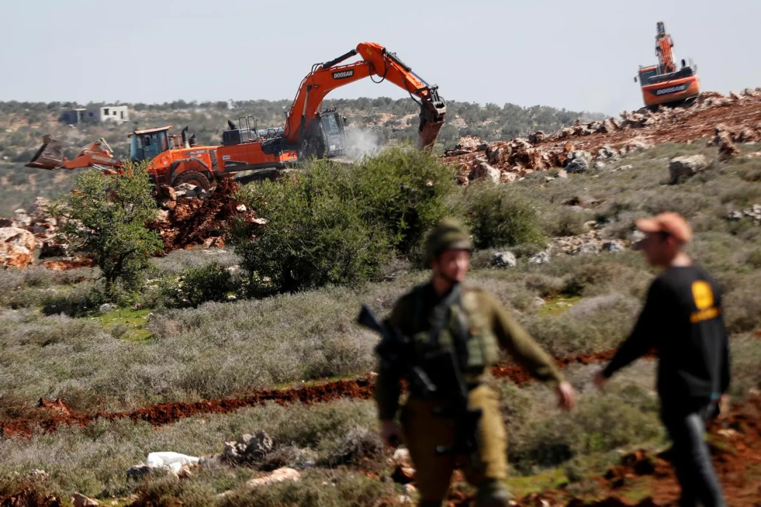 Israeli machineries, guarded by Israeli forces, bulldoze lands near the Palestinian village of Qusra, in the Israeli occupied West Bank, March 3, 2020. (Reuters)