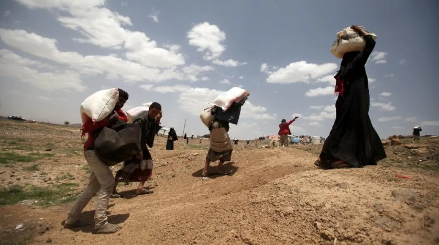 People carry food aid received from a local charity ahead of the holy month of Ramadan on the outskirts of Sanaa, Yemen, May 5, 2019. (Reuters)
