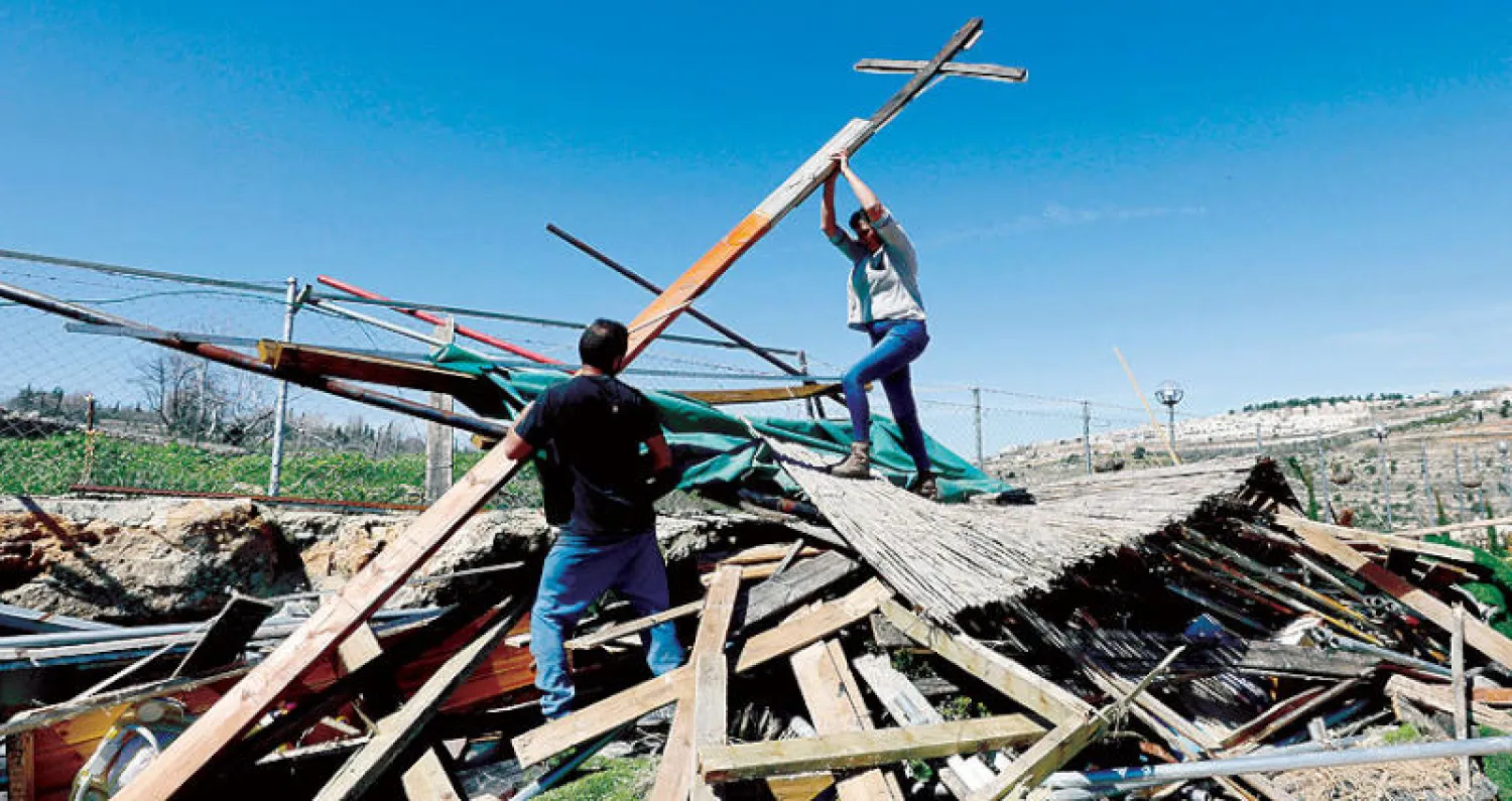 فلسطينيان من بيت جالا في الضفة الغربية وسط أنقاض مبنى هدمه مستوطنون أمس (رويترز)