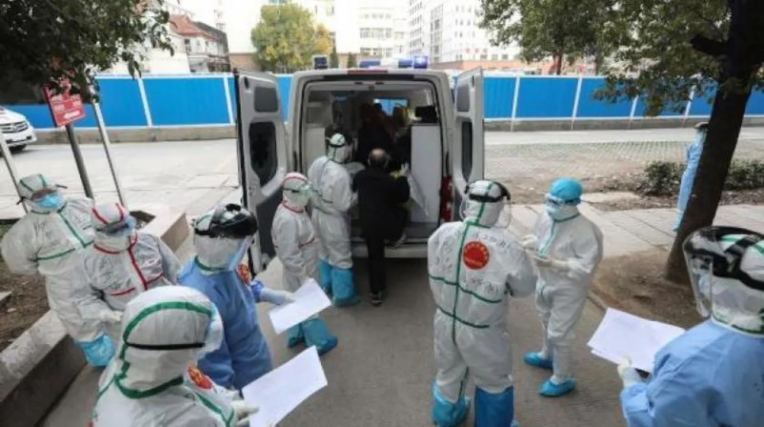 طاقم طبي يساعد مصاباً بفيروس كورونا للانتقال إلى مستشفى آخر في ووهان (أ.ف.ب)