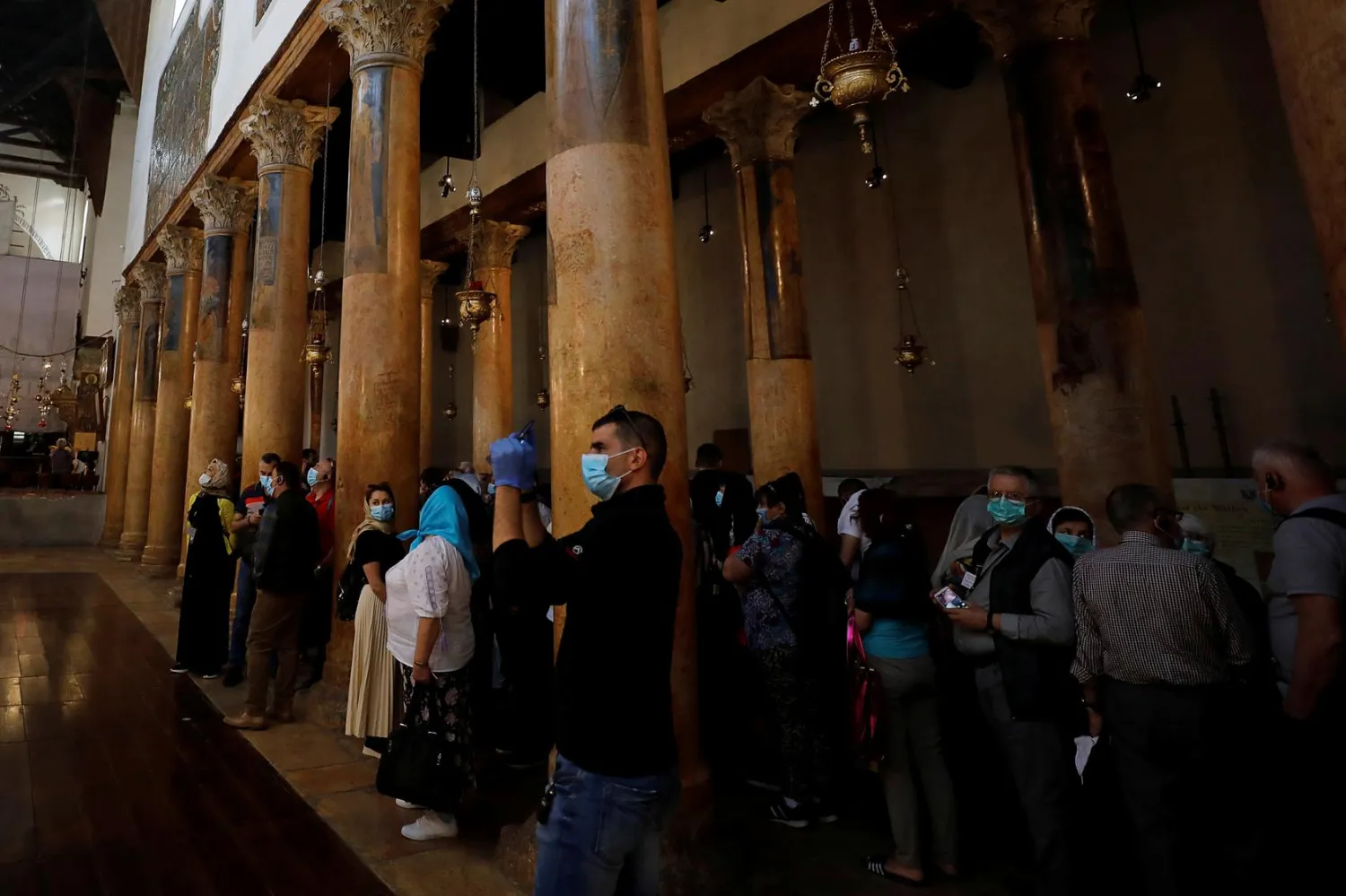A visitor wearing a mask as a preventive measure against the coronavirus takes pictures in the Church of the Nativity in Bethlehem in the Israeli-occupied West Bank March 5, 2020. REUTERS/Mussa Qawasma
