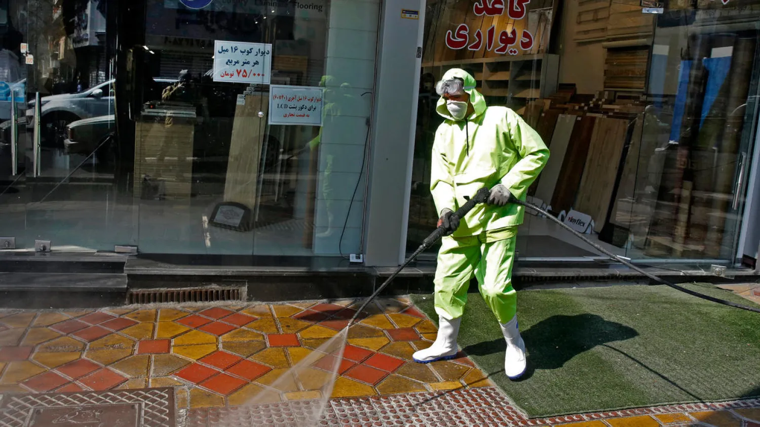 Iranian municipality worker disinfects a street in the capital Tehran as the country struggles to contain a rapid spread of coronavirus | AFP