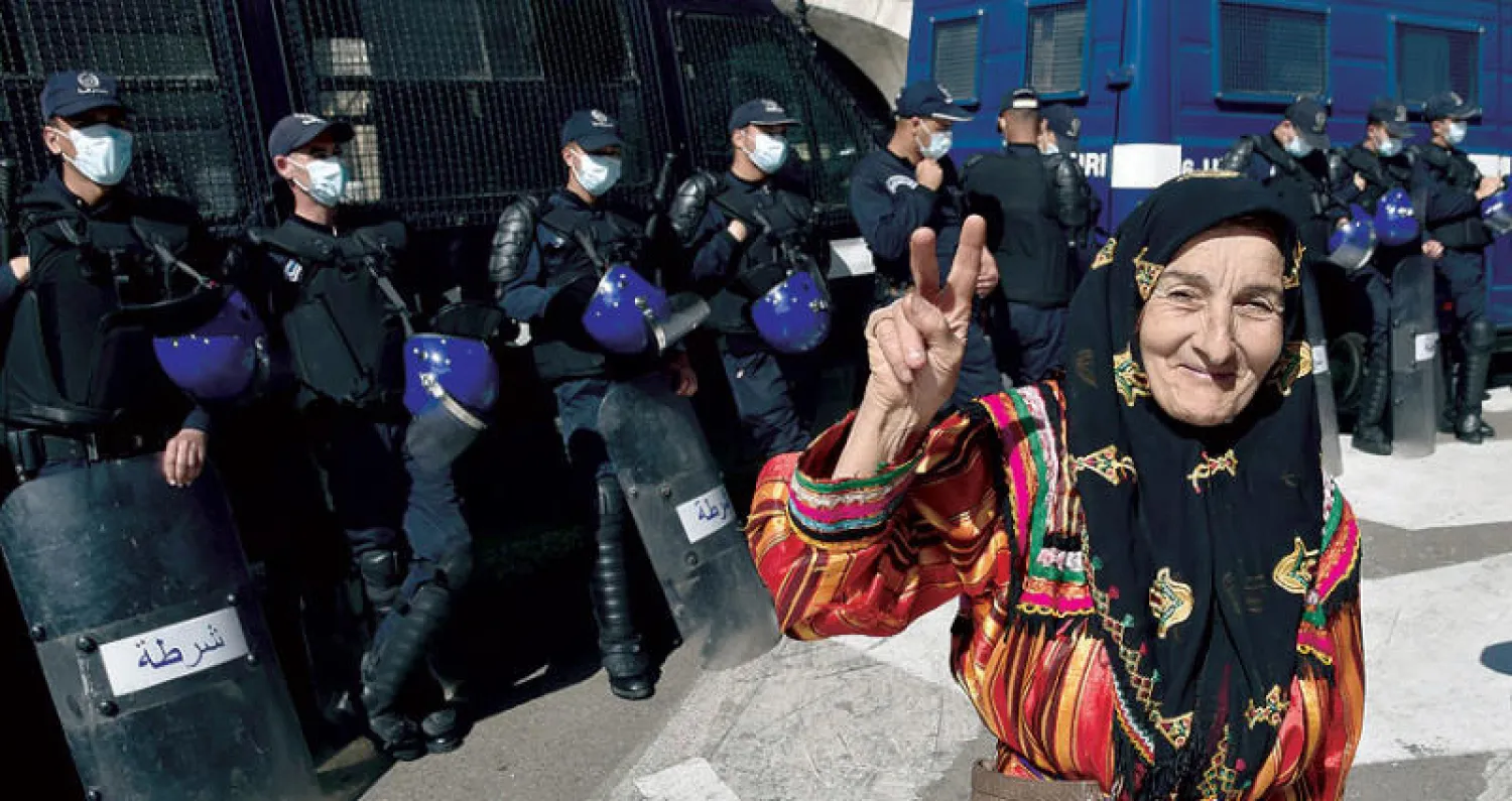 مواطنة جزائرية شاركت في مظاهرات أول من أمس ترفع شارة النصر أمام قوات الأمن التي حاصرت المتظاهرين (أ.ف.ب)