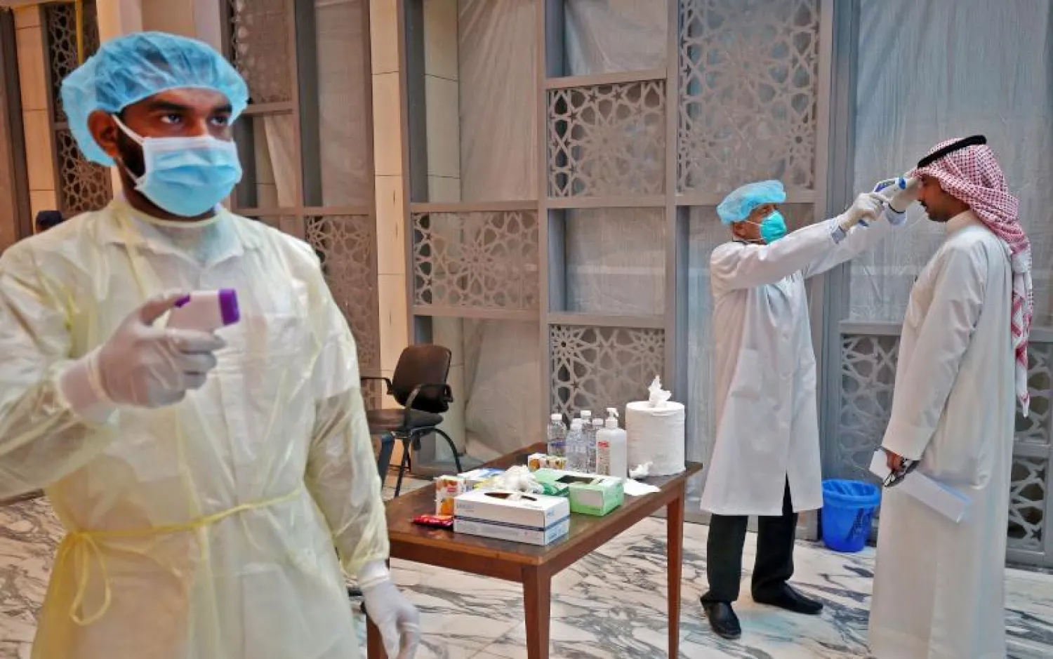 فحص حرارة الموظفين والزائرين لمجمع الوزارات بالعاصمة الكويتية (أ.ف.ب)