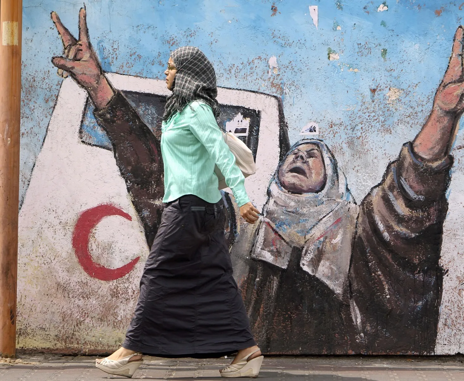 A woman walks past a mural in Gaza City. (Reuters) 