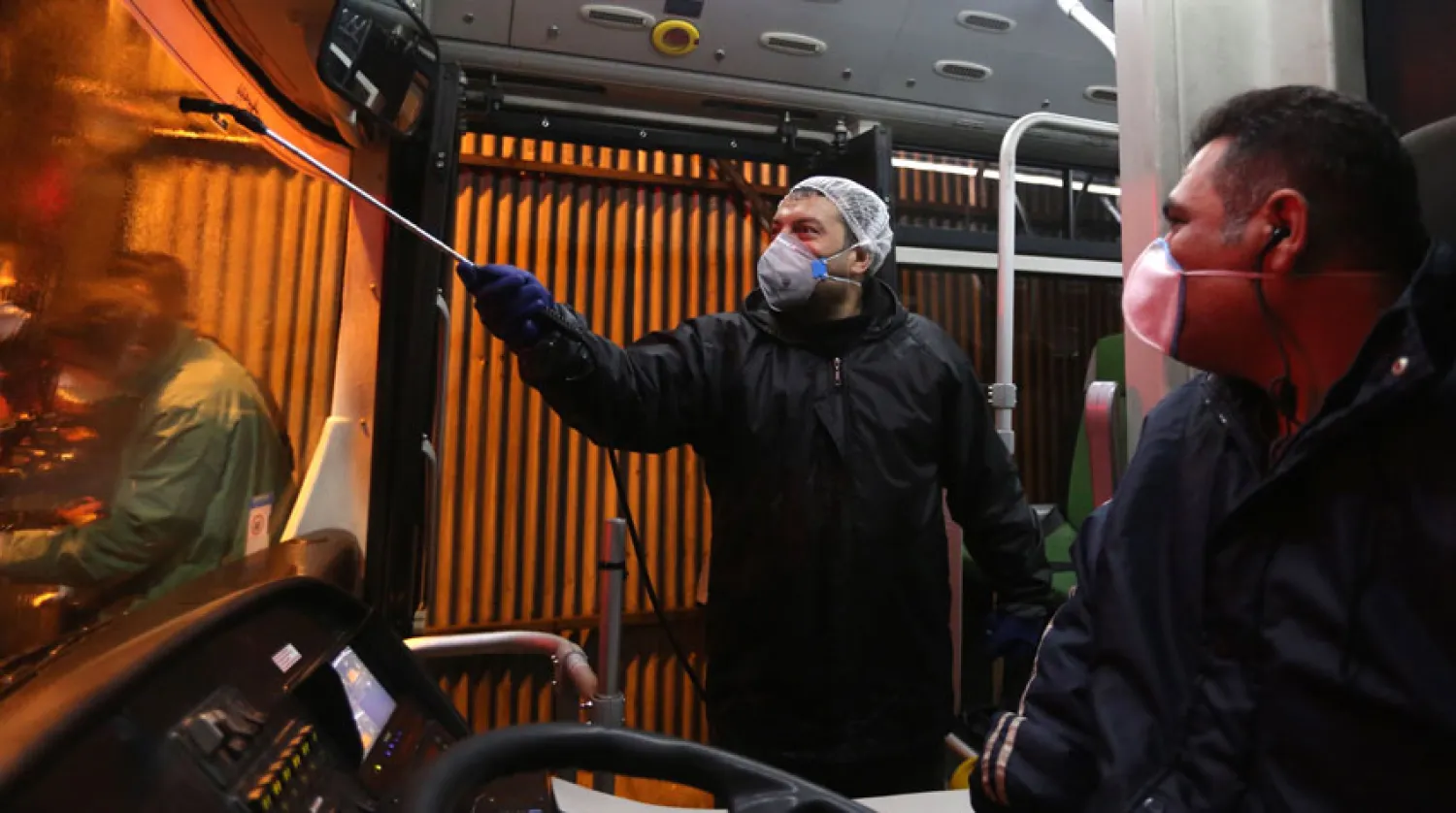 عامل بلدية يرش حافلة مسافرين في طهران لمنع انتشار الفيروس. (أ.ف.ب)