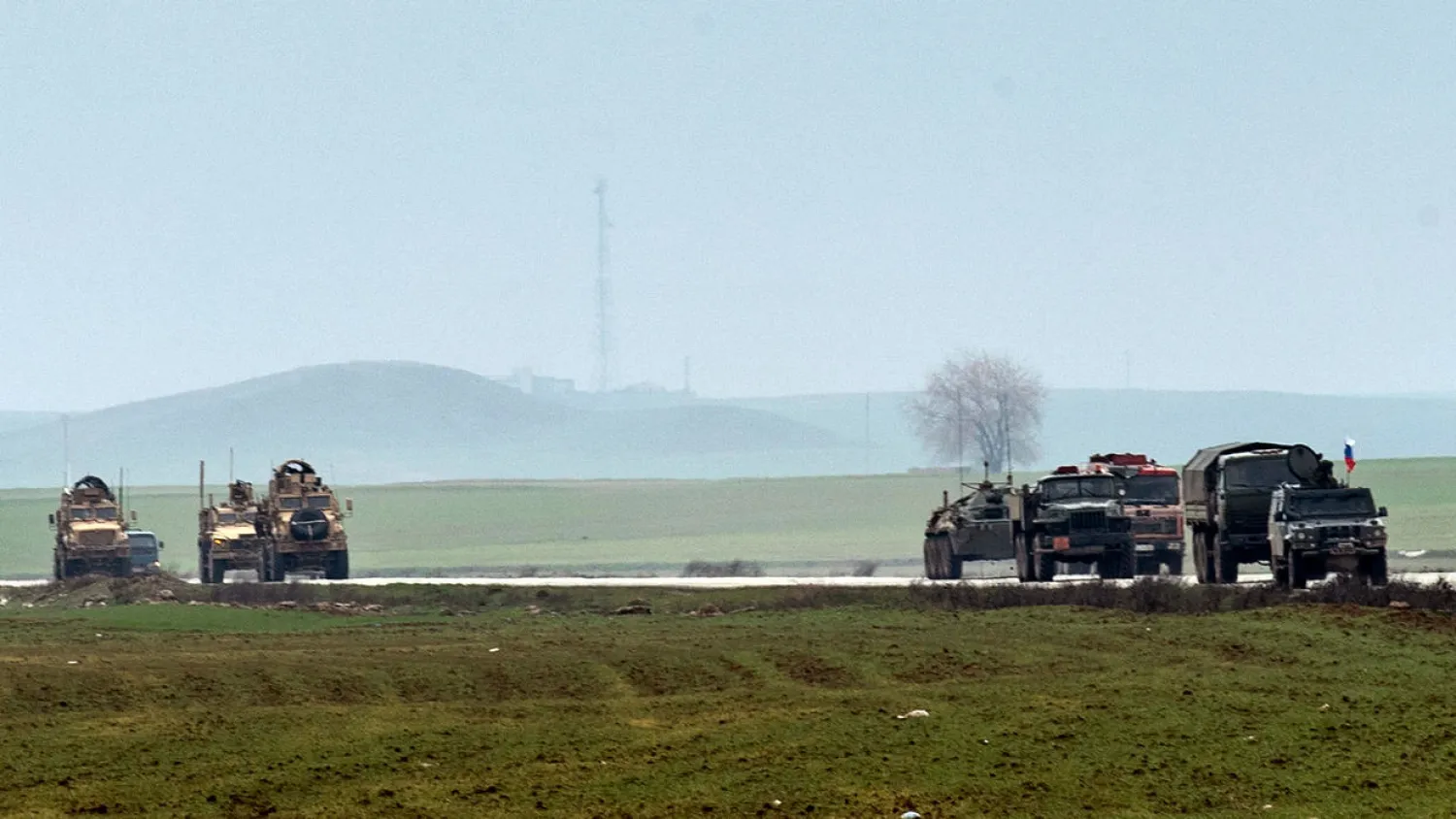 A US military convoy (L) and a Russian patrol are seen in this January picture crossing paths on the key M4 highway in Syria's northeastern Hasakeh province | AFP