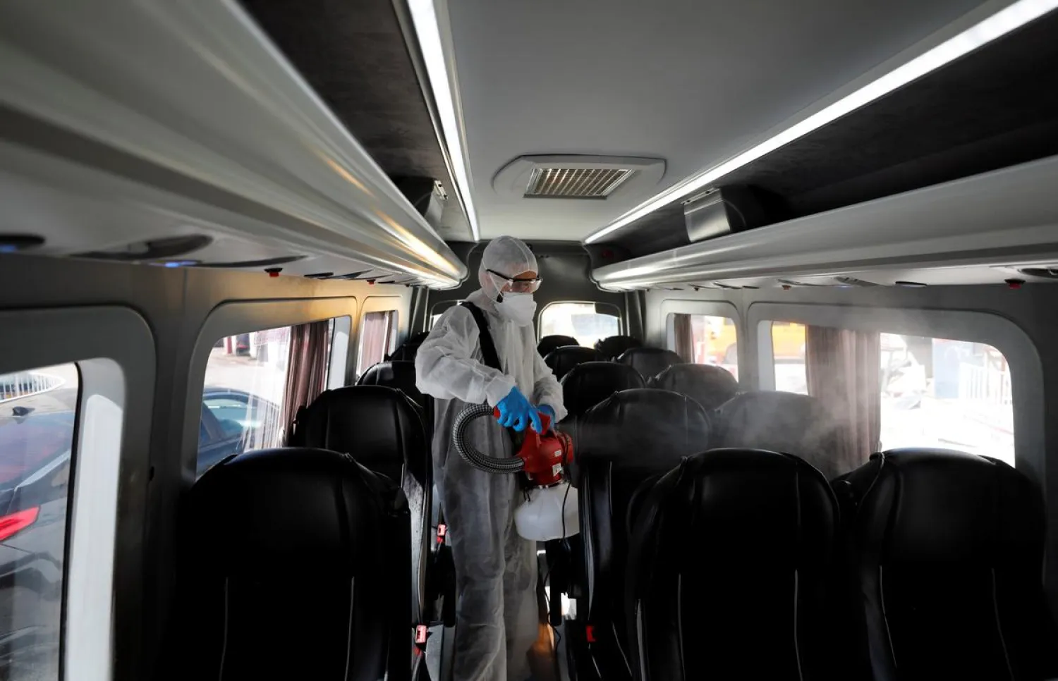 A Palestinian worker in a protective suit disinfects a bus as a preventive measure against the coronavirus in Beit Jala town in the Israeli-occupied West Bank on March 5, 2020. (Reuters)