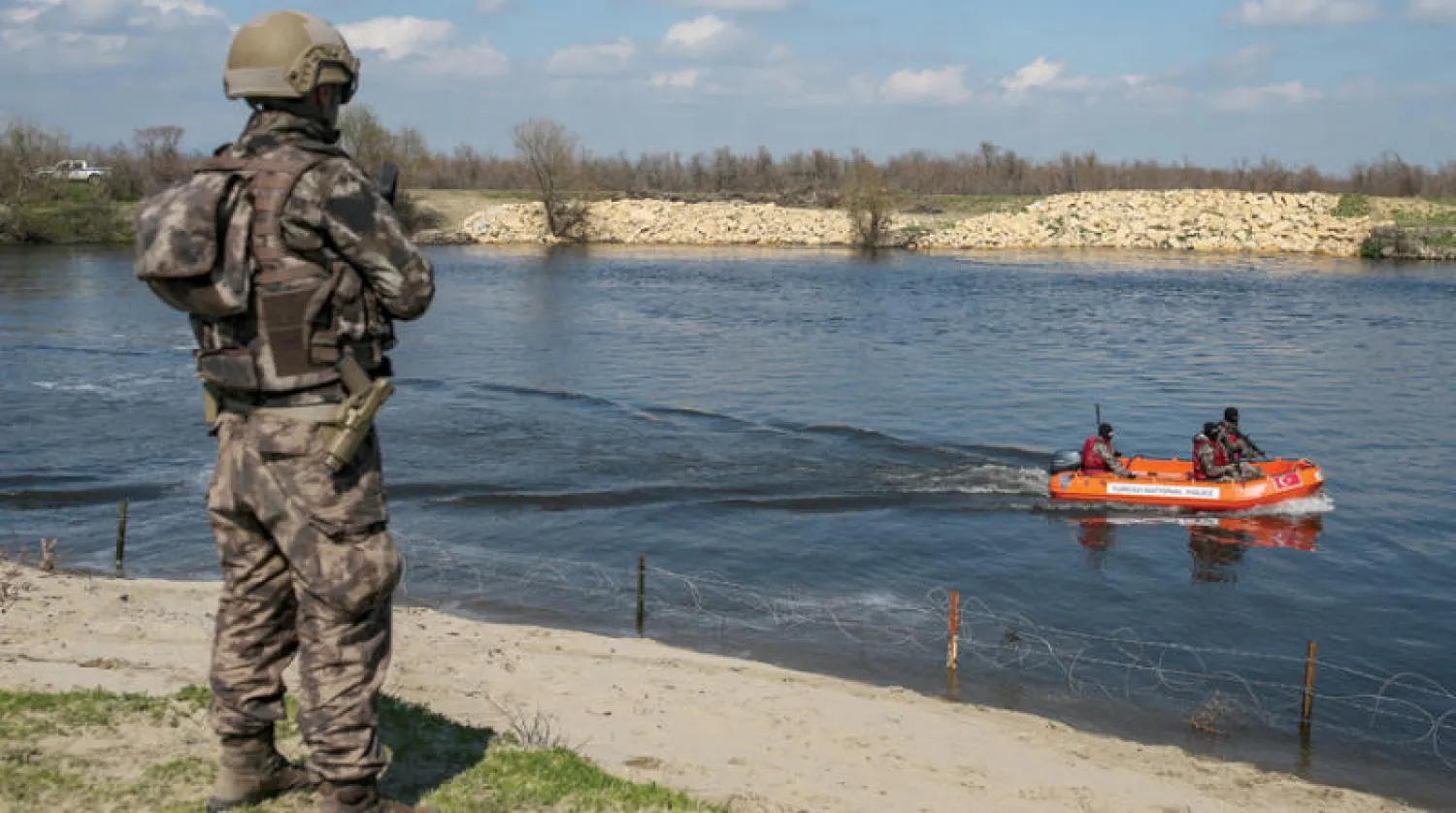 جندي يوناني يراقب قارباً مطاطياً تركياً على الحدود البحرية بين البلدين (أ.ب)