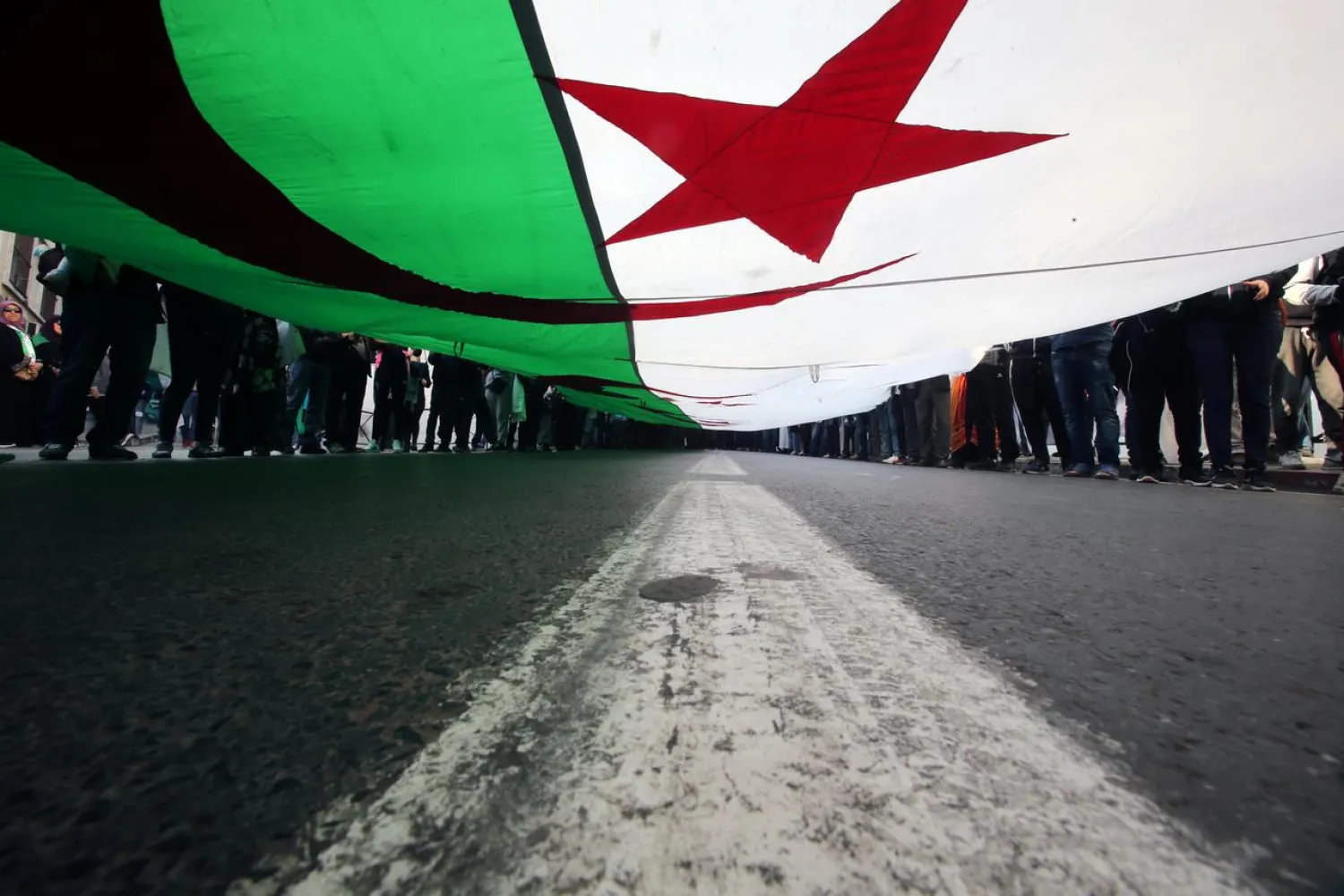  Demonstrators carry a national flag as they march, a year since the start of weekly protests calling for a complete overhaul of the ruling elite, an end to corruption and the army's withdrawal from politics, in Algiers, Algeria, February 14, 2020. REUTERS/Ramzi Boudina
