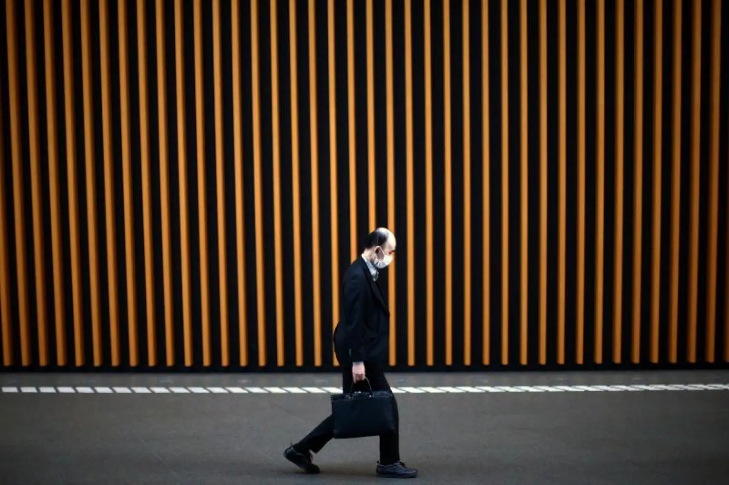 رجل يرتدي قناعاً واقياً خوفاً من فيروس كورونا المستجد في طوكيو (رويترز)