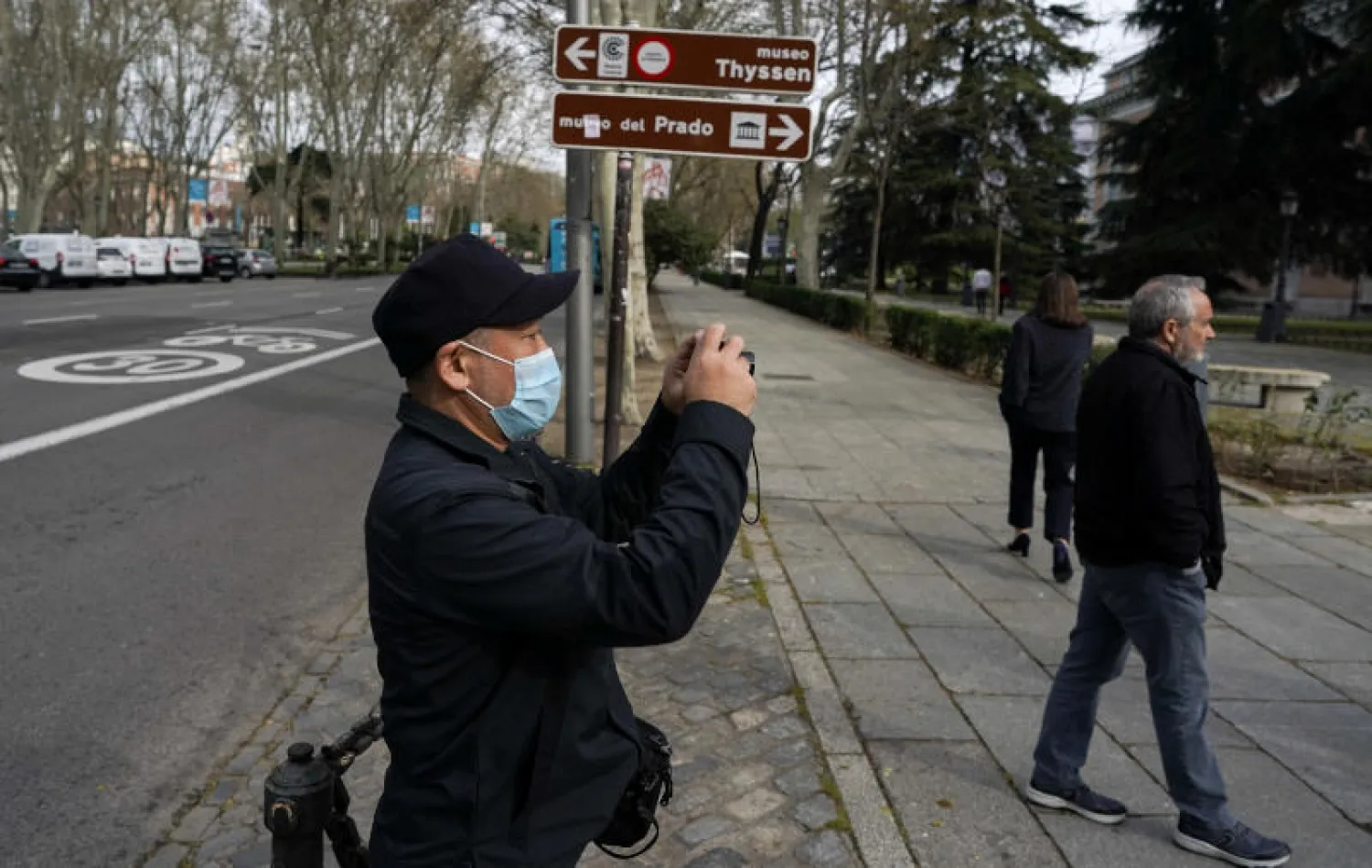 رجل يرتدي كمامة للحماية خارج أحد المزارات السياحية في مدريد (رويترز)