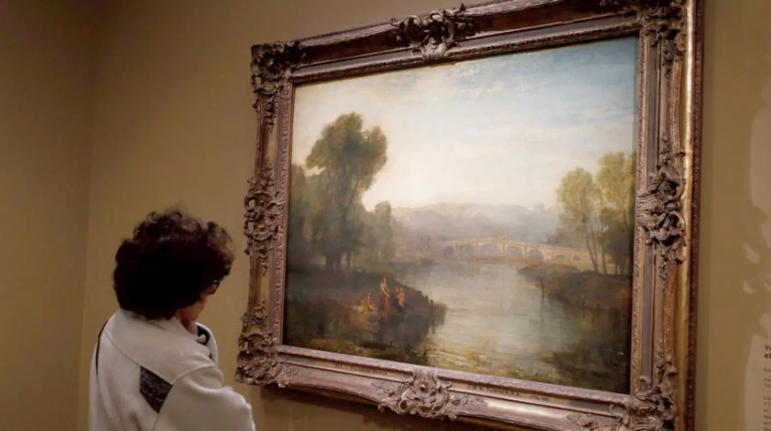امرأة تتأمل لوحة  للفنان البريطاني تيرنر بالمعرض في باريس (أ.ف.ب)