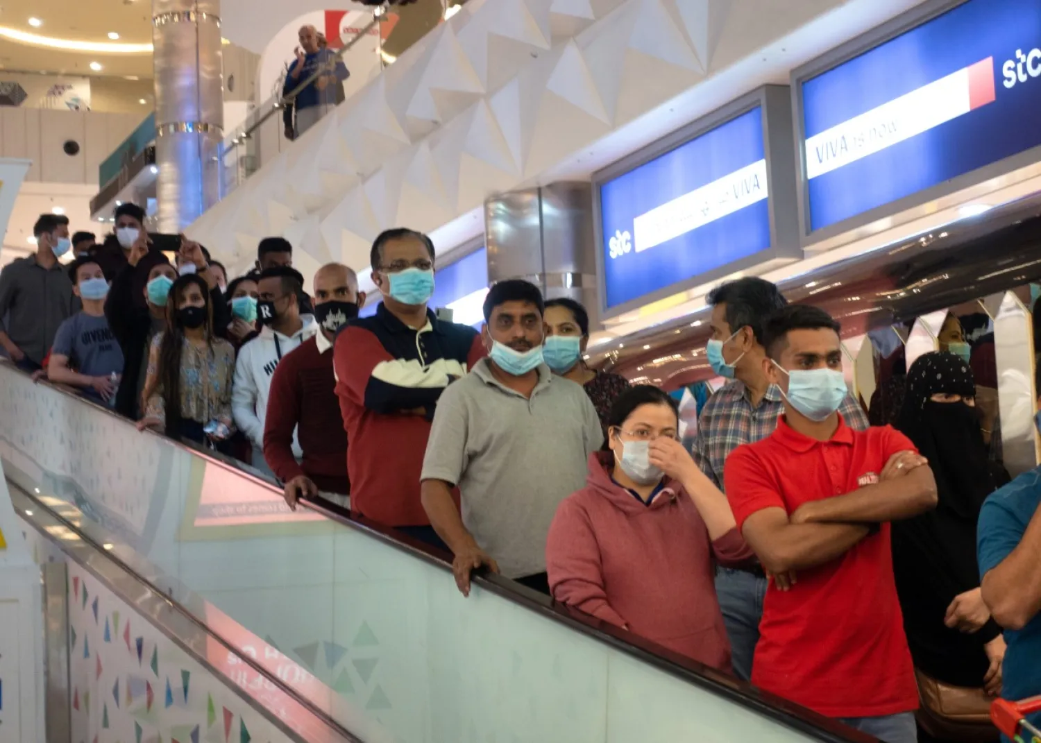 People in protective masks, following the coronavirus outbreak, ride the escalator at a supermarket to stock up on food in Salmiya, after Kuwait's government announced mandatory work leave for all people in Kuwait, March 11, 2020. REUTERS/Stephanie McGehee