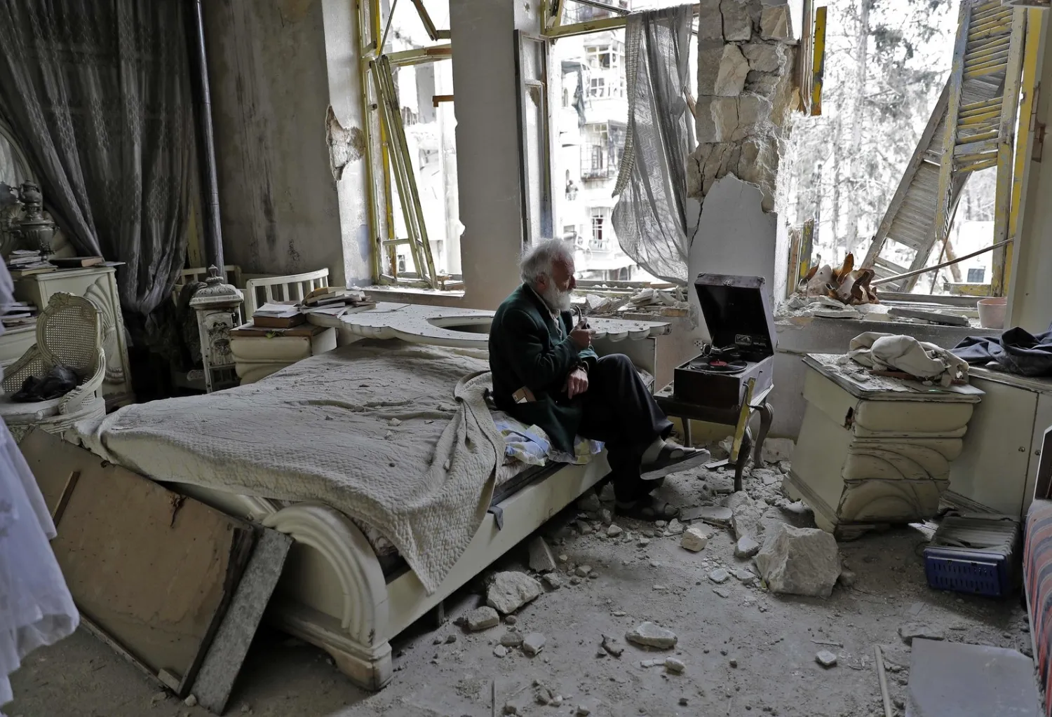 A Syrian man smokes his pipe in his destroyed bedroom in Aleppo's formerly rebel-held Shaar neighborhood on March 9, 2017 | AFP