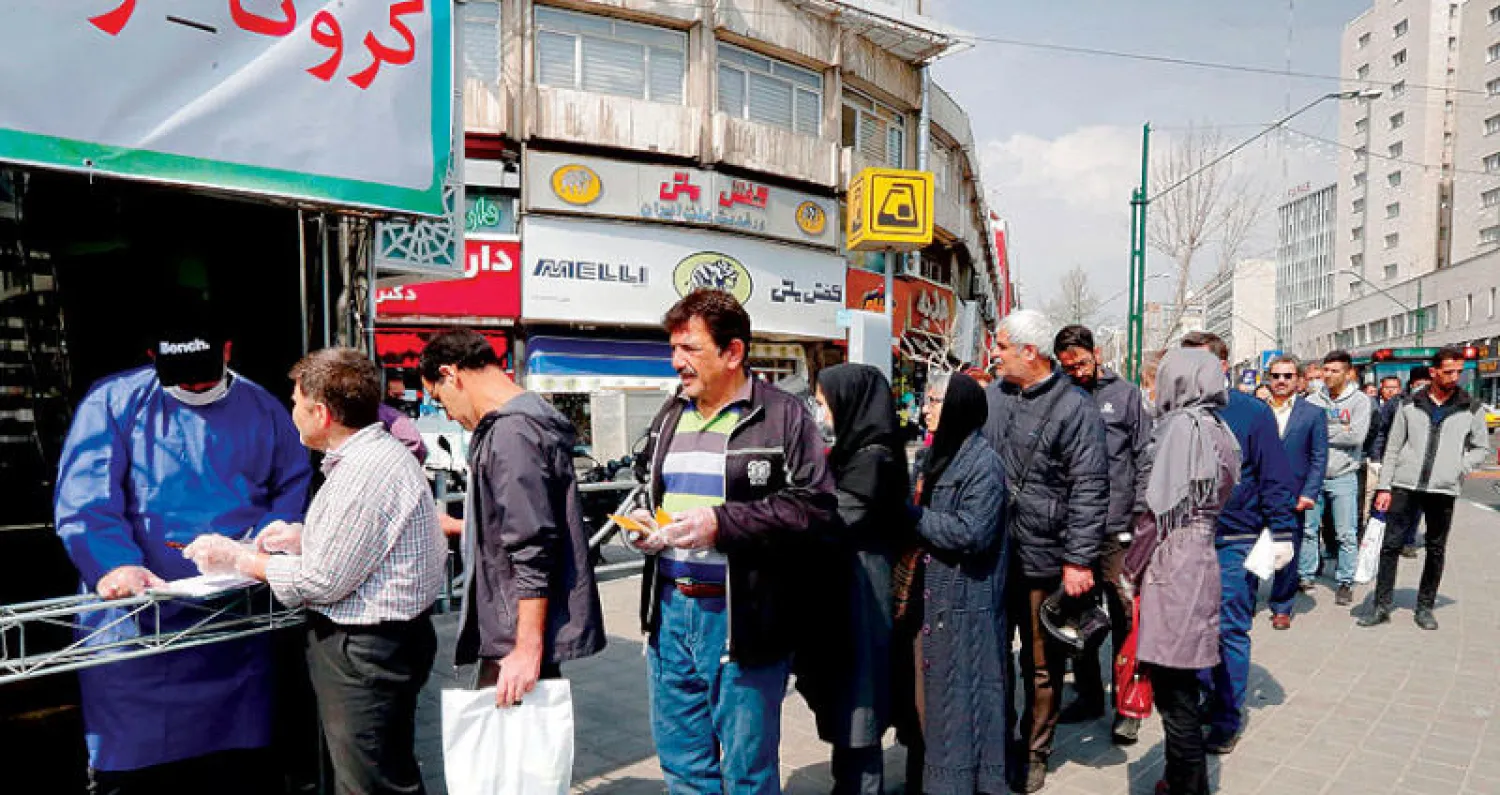 مركز يوزع الكمامات والقفازات للإيرانيين بميدان «ولي عصر» وسط طهران أمس (أ.ف.ب)