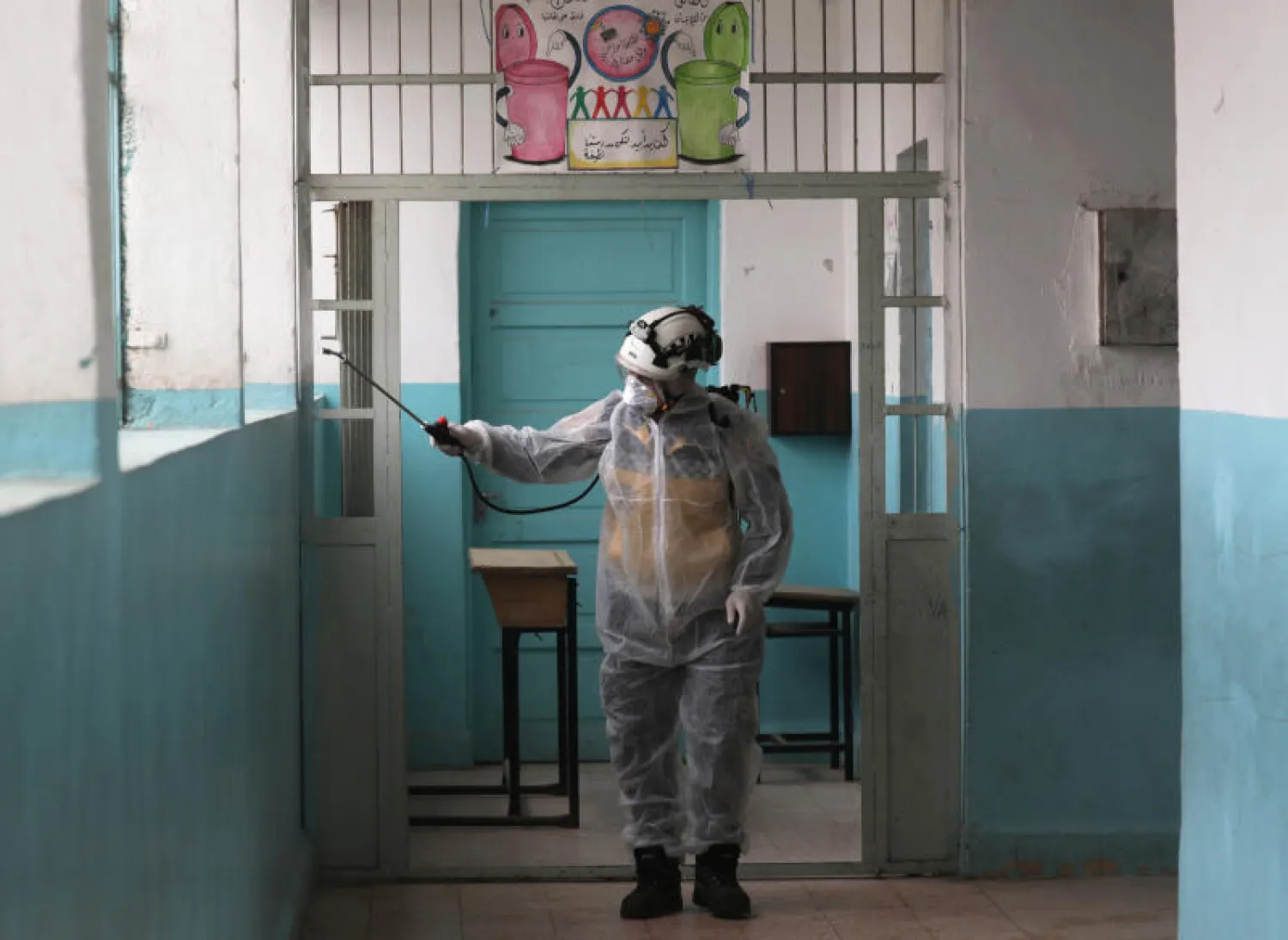 عنصر من الدفاع المدني بسوريا يقوم يتعقيم إحدى المدارس في عفرين (رويترز)