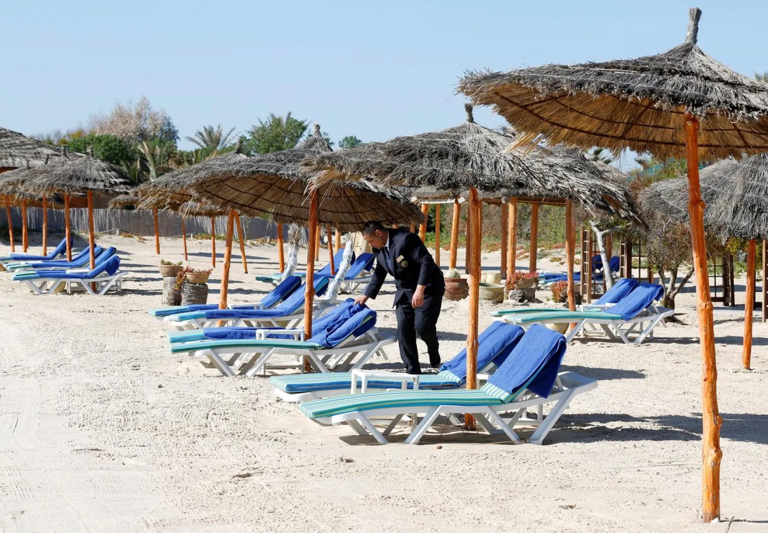 An employee arranges sunbathing chairs on a beach near the Hasdrubal Hotel in Hammamet, Tunisia, March 12, 2020. (Reuters)
