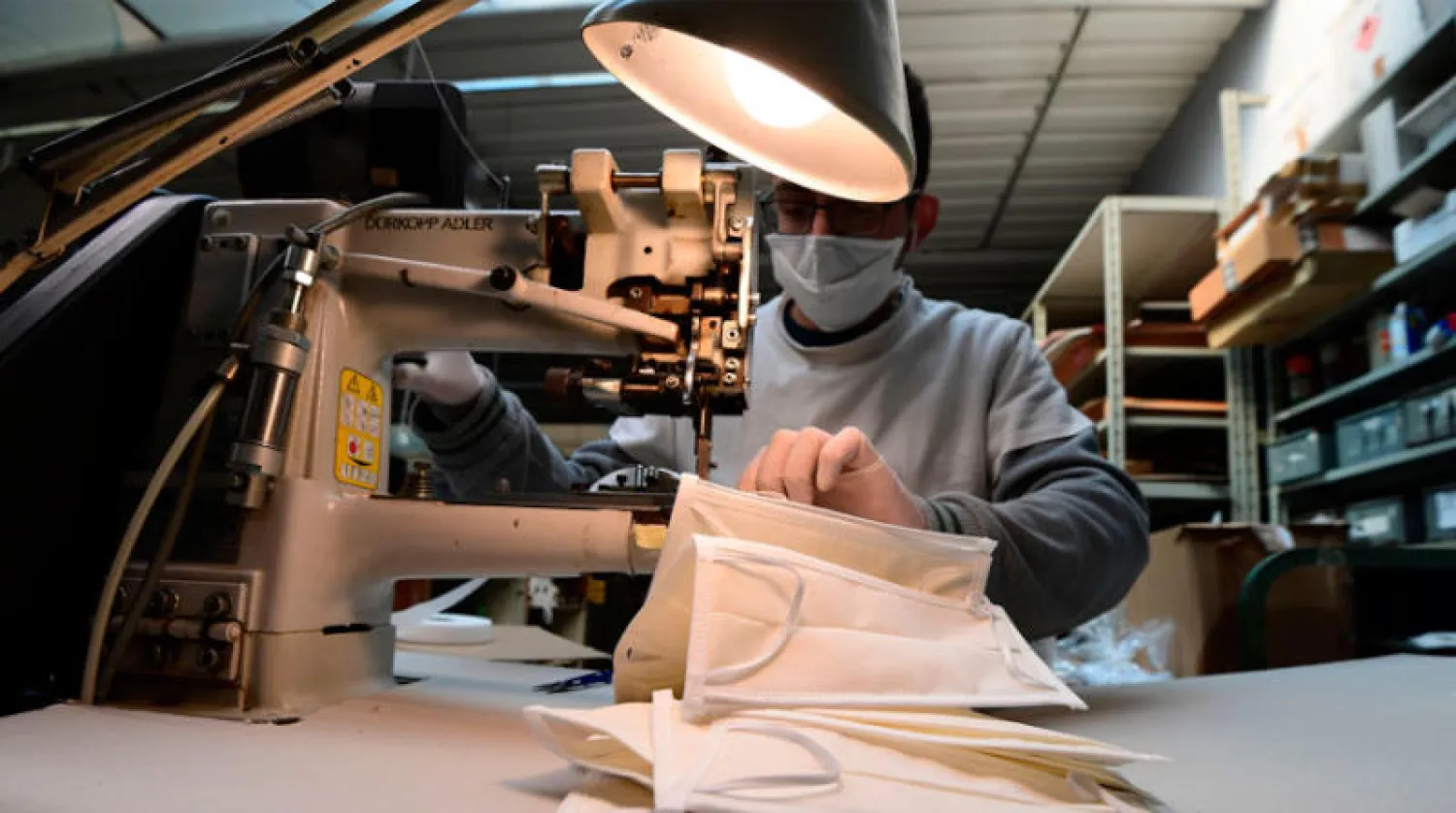 عامل في مصنع إيطالي للمنتجات الجلدية يجهّز أقنعة واقية بعد أن حول المصنع نشاطه إلى صناعتها (أ.ف.ب)