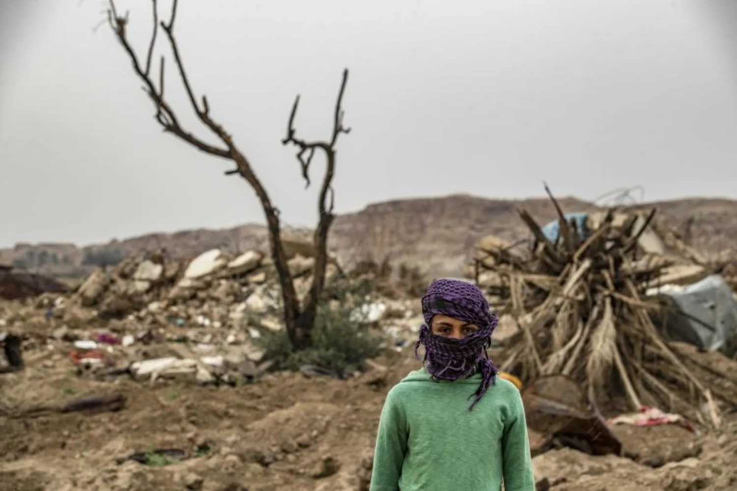 طفل يقف أمام أرض جده المتضررة جراء انتشار تنظيم «داعش» في قرية الباغوز بشرق سوريا (أ.ف.ب)