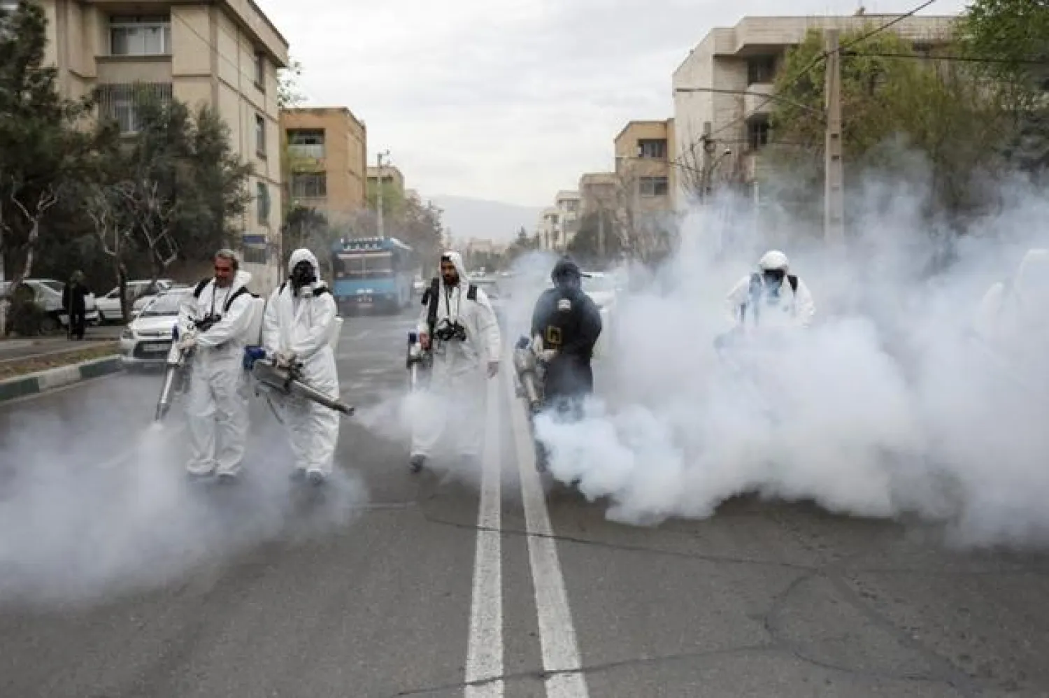 FILE PHOTO: Members of firefighters wear protective face masks, amid fear of coronavirus disease (COVID-19), as they disinfect the streets, in Tehran, Iran March 18, 2020. Reuters