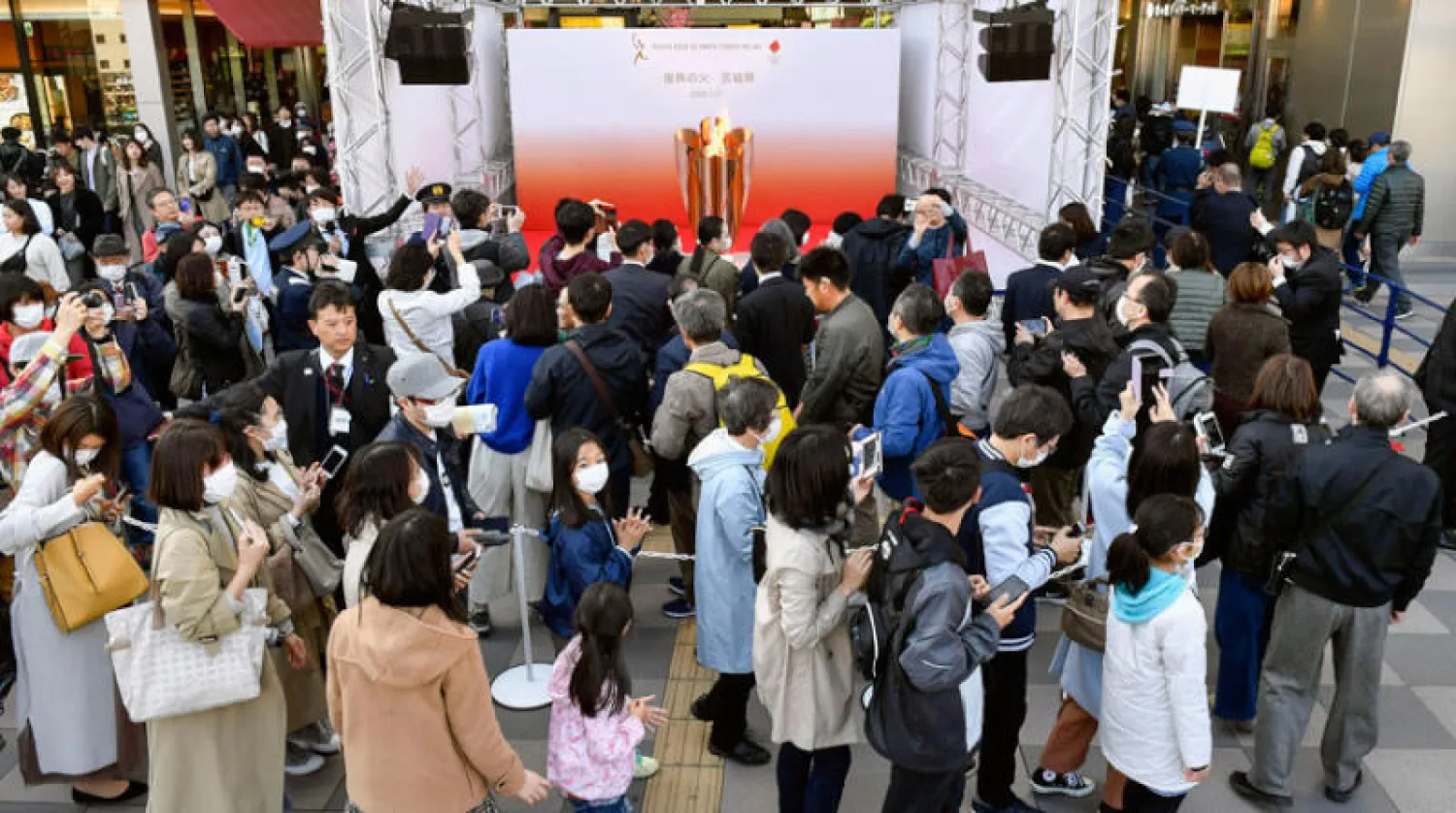 طابور من اليابانيين يرتدون الأقنعة في طريقهم لإلقاء نظرة على شعلة الأولمبياد (أ.ب)