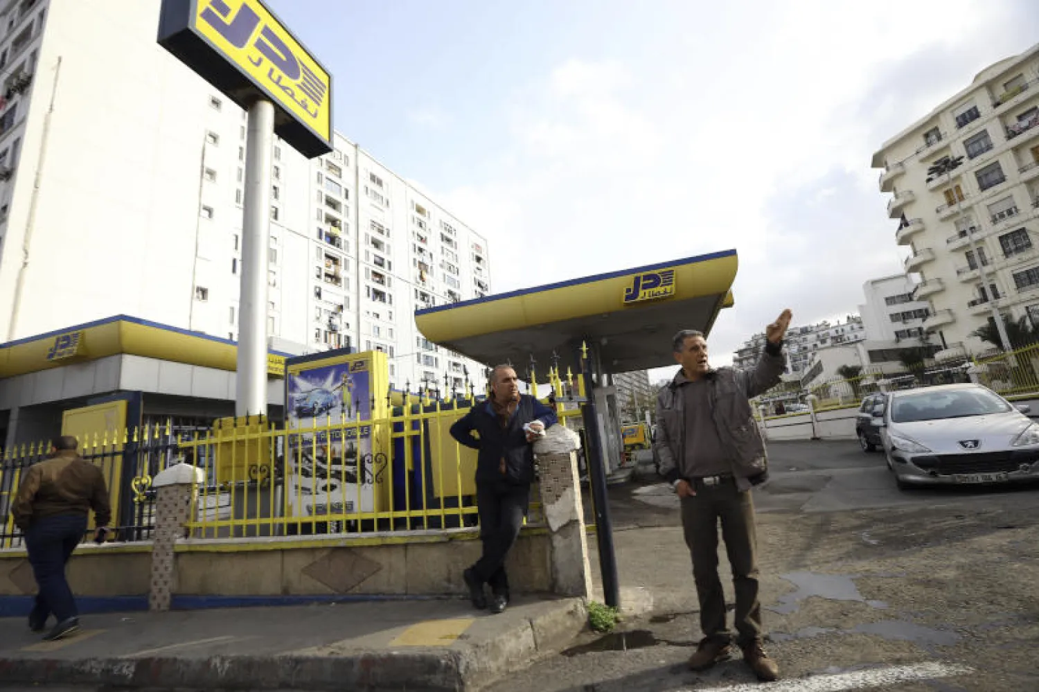 عمال خارج إحدى محطات الوقود في الجزائر (أ.ب)