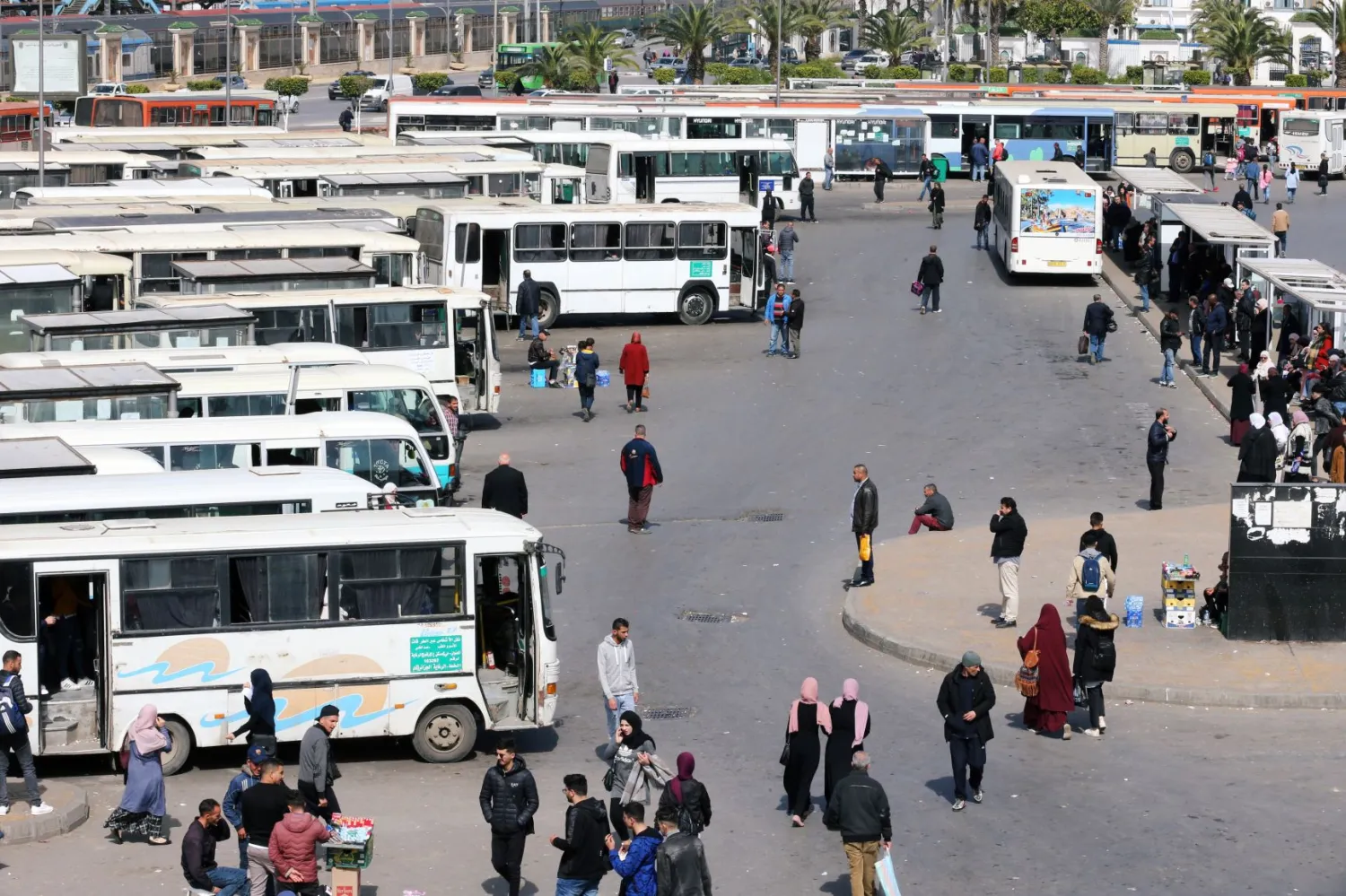 جزائريون في إحدى محطات الحافلات في العاصمة (رويترز)