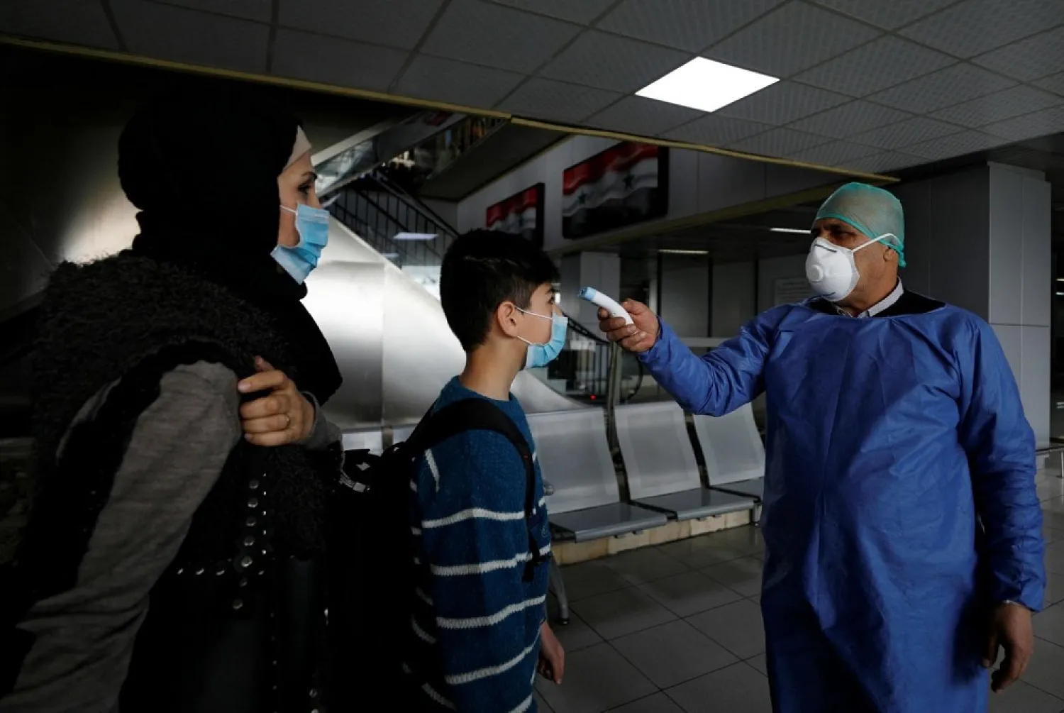 A health official tests passengers at Damascus International Airport as part of security measures to avoid spreading coronavirus. (Reuters)